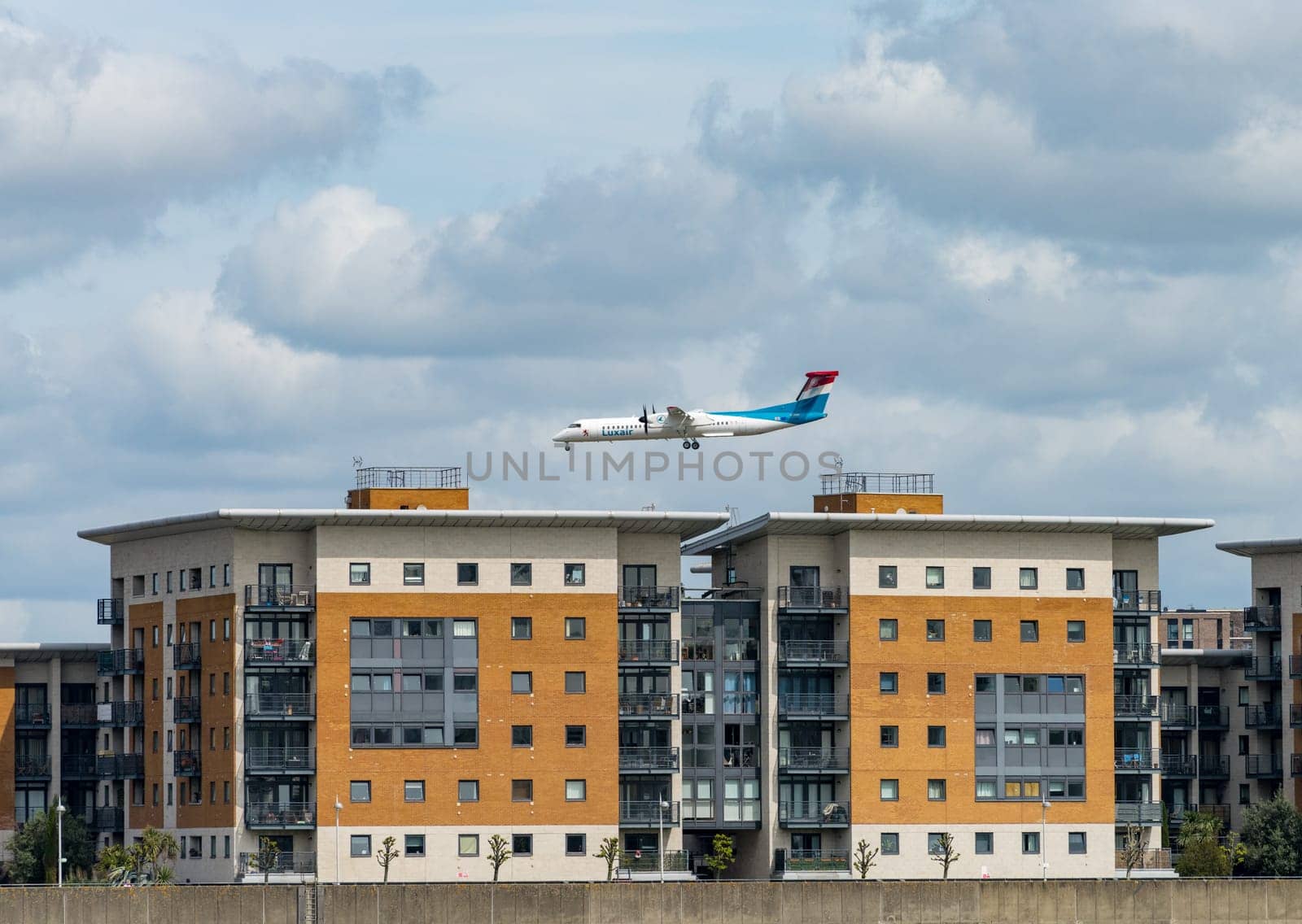 Woolwich, London - 15 May 2023: Luxair plane flying low over apartment block for landing at City Airport