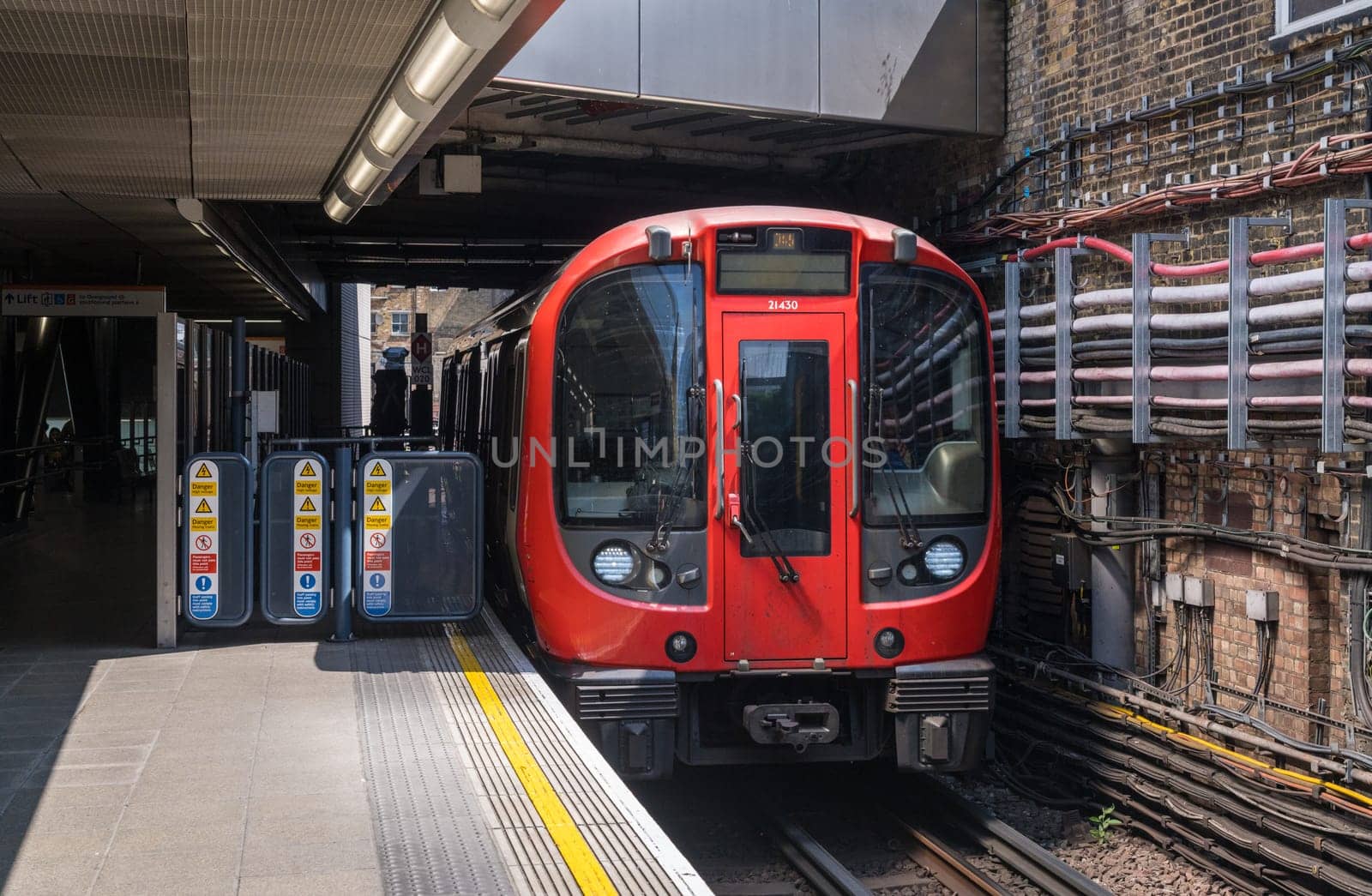 Whitechapel, London - 14 May 2023: London District Line tube train entering the station into sunlight