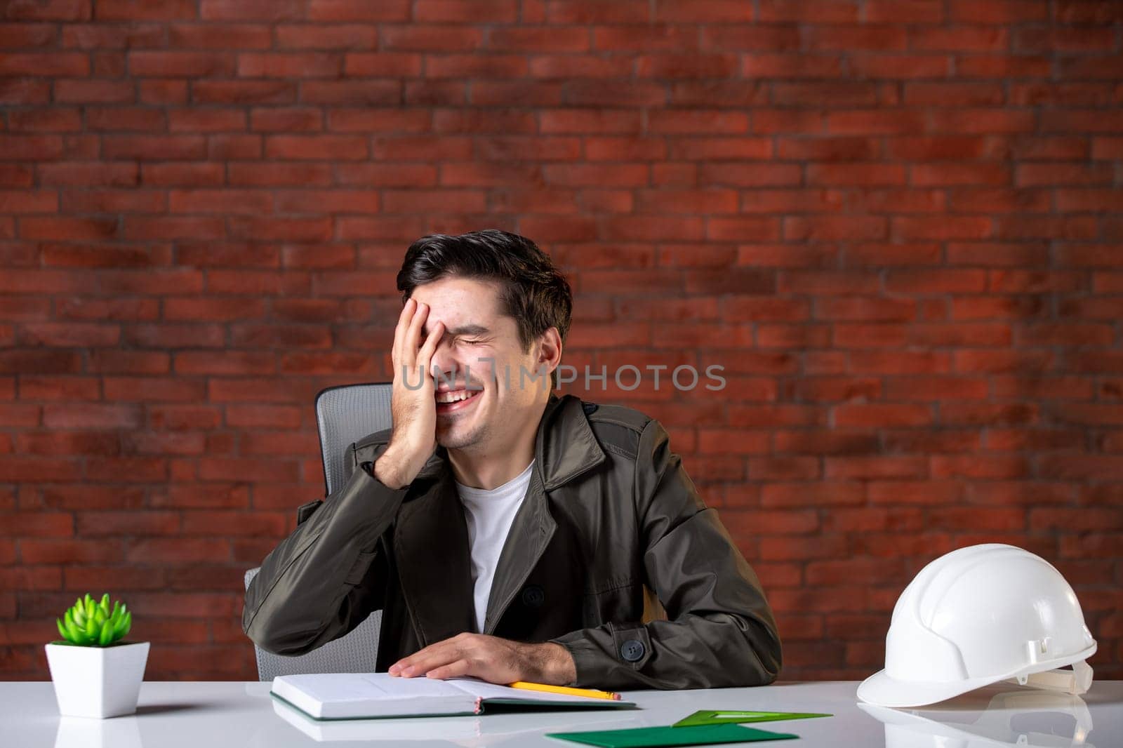 front view laughing male engineer sitting behind his working place job contractor agenda corporate business builder property plan