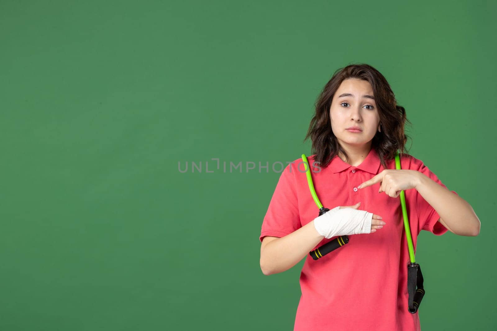 front view young pretty saleswoman with bandage on her hurt hand on a green background job injury health hospital color pain work