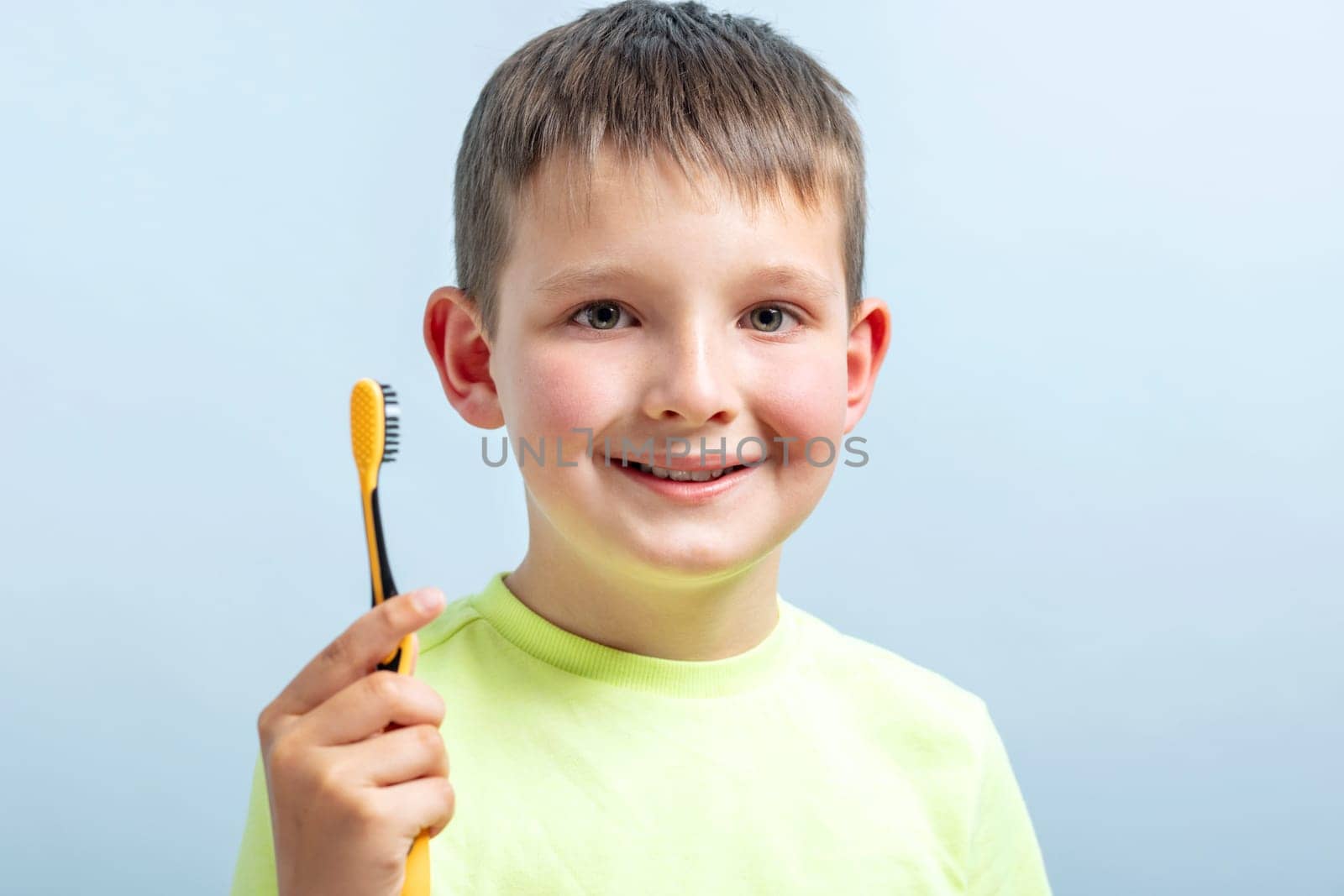 Happy child kid boy with toothbrush on blue background. Health care, dental hygiene. Mockup, copy space.