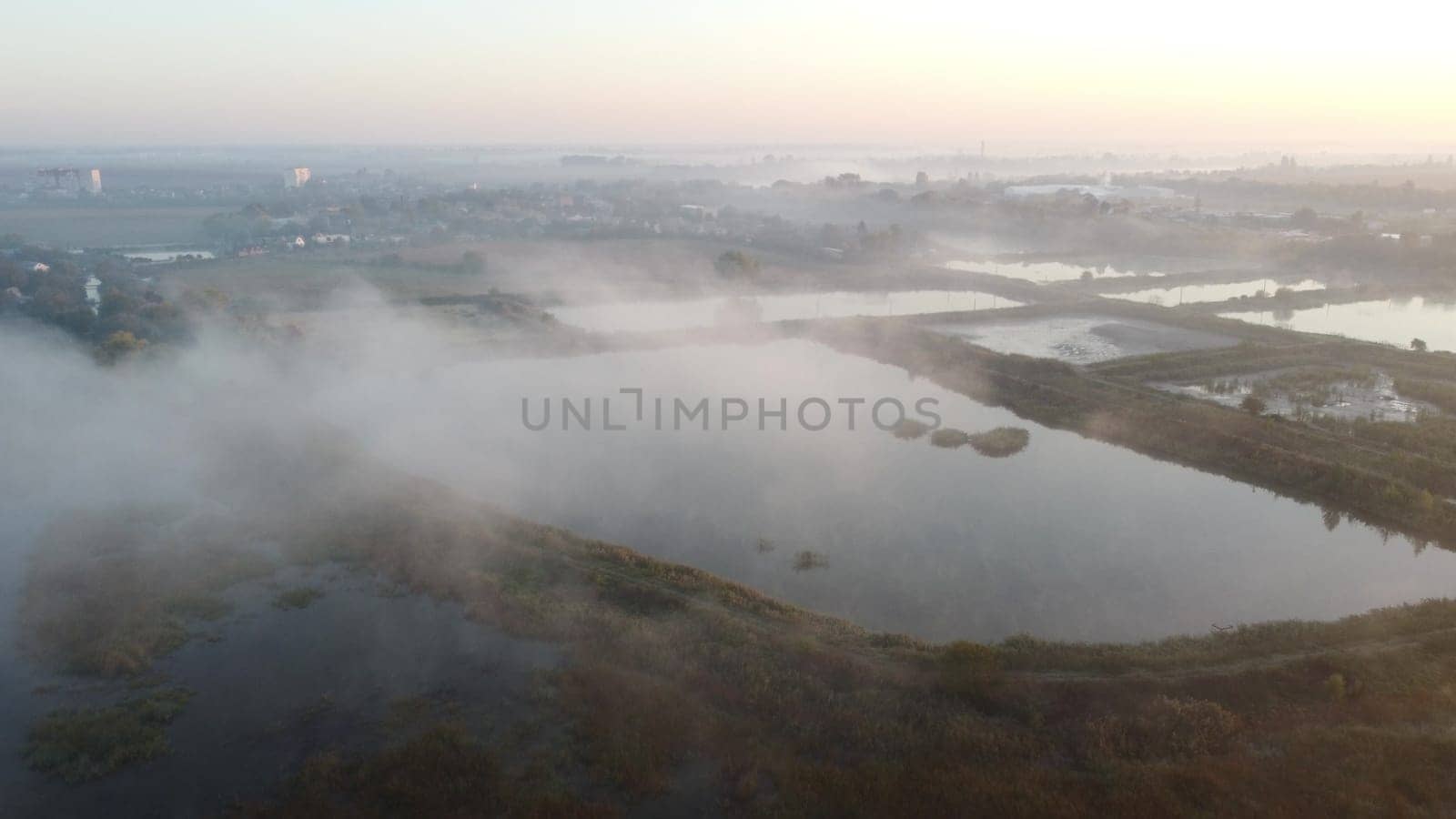 Lakes, artificially created water ponds for growing fish farming with morning mist on an early summer sunny morning. Nature scenery, natural landscape. Sunlight, sunshine. Top view. Aerial drone view.