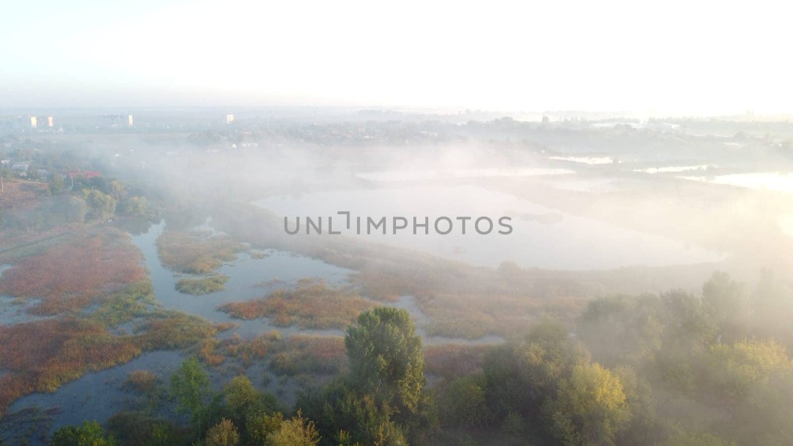 Lakes, artificially created water ponds for growing fish farming with morning mist on an early summer sunny morning. Nature scenery, natural landscape. Sunlight, sunshine. Top view. Aerial drone view.