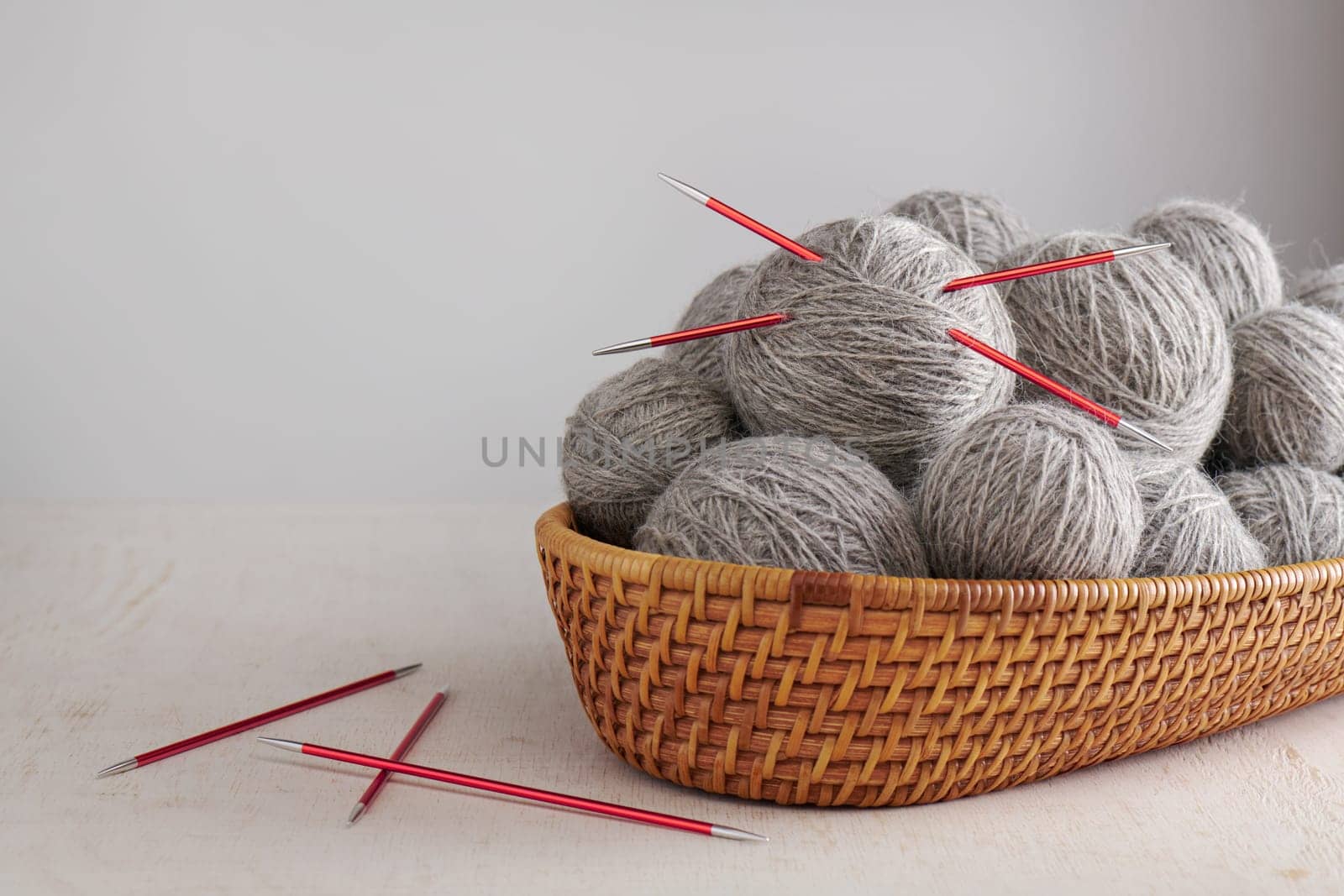 Double pointed knitting needles and balls of yarn in basket