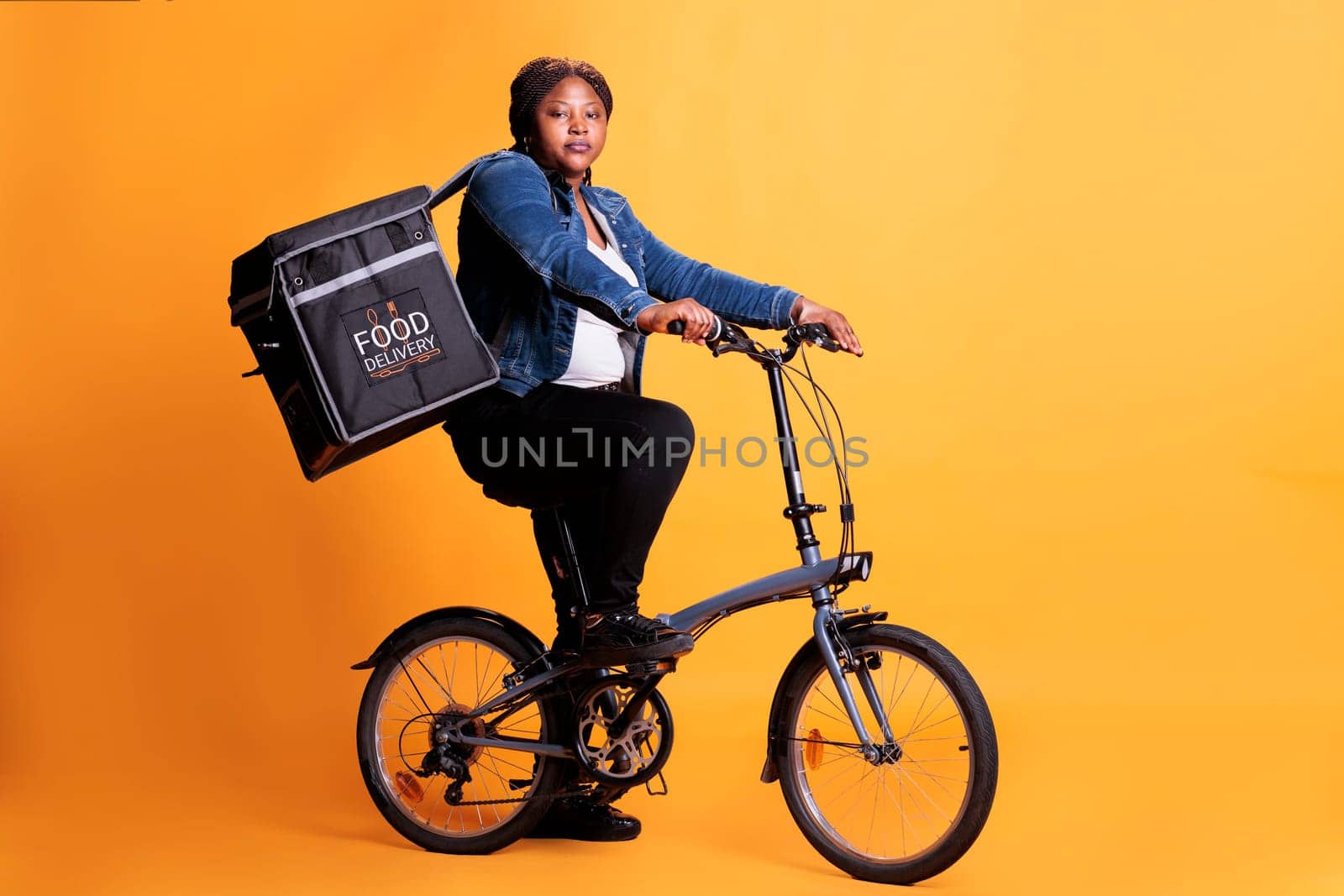 Food delivery employee riding bike while carrying takeaway thermal backpack ready to deliver order to client by DCStudio