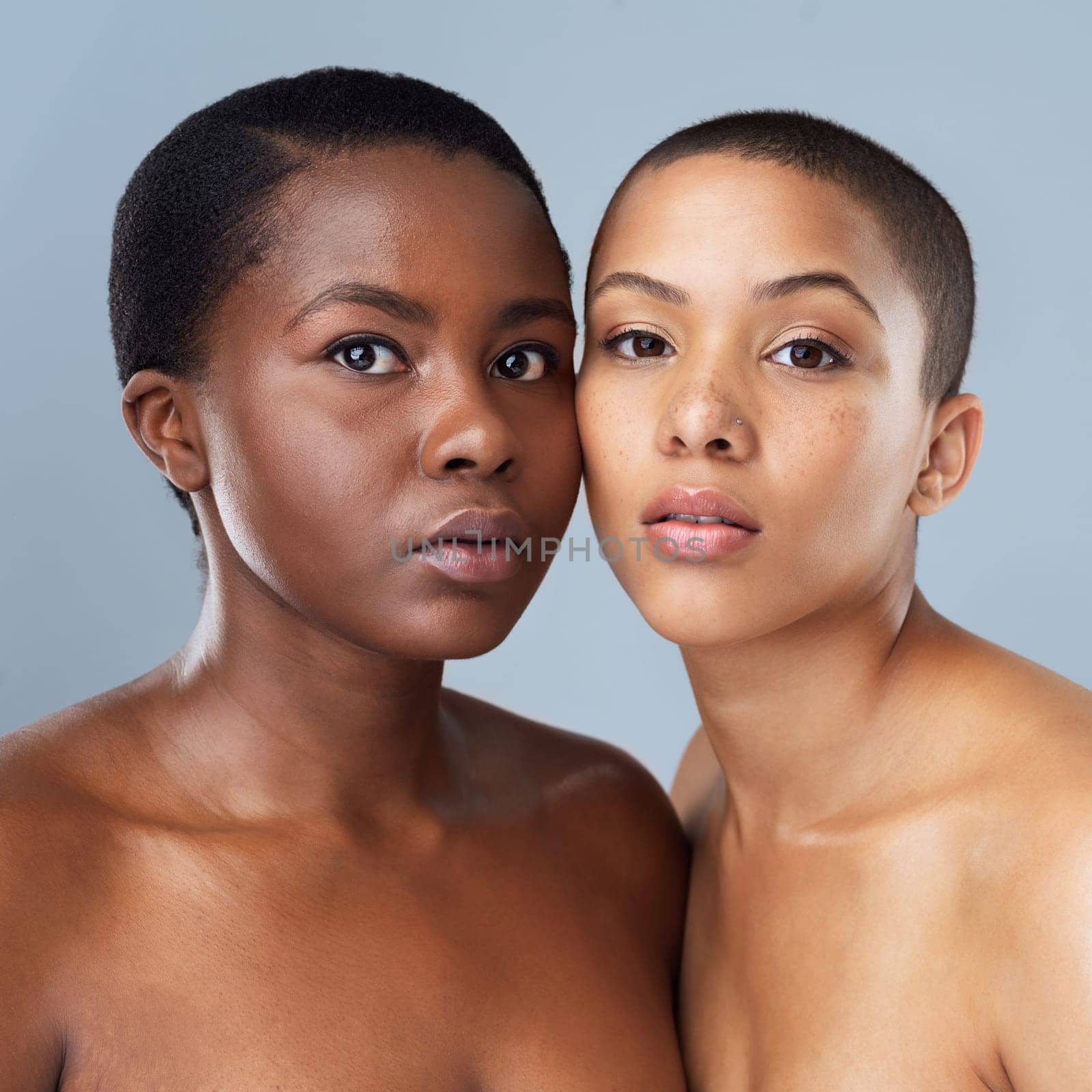 We can be serious too. Portrait of two beautiful young women standing close to each other against a grey background