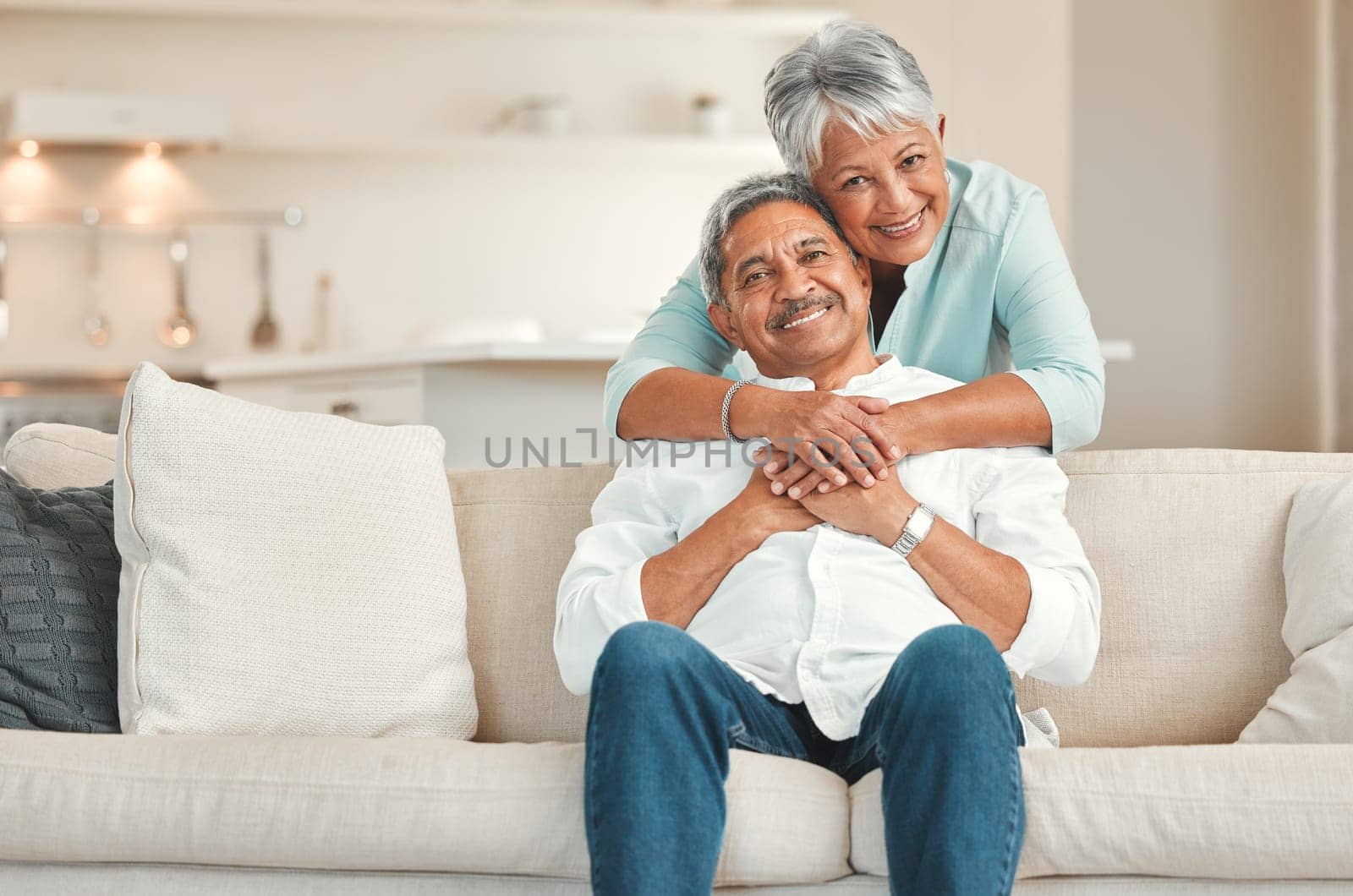 Senior couple, couch and portrait with hug, smile and love in home living room with care, romance or happiness. Elderly man, old woman and embrace by lounge sofa in relax retirement together in house.