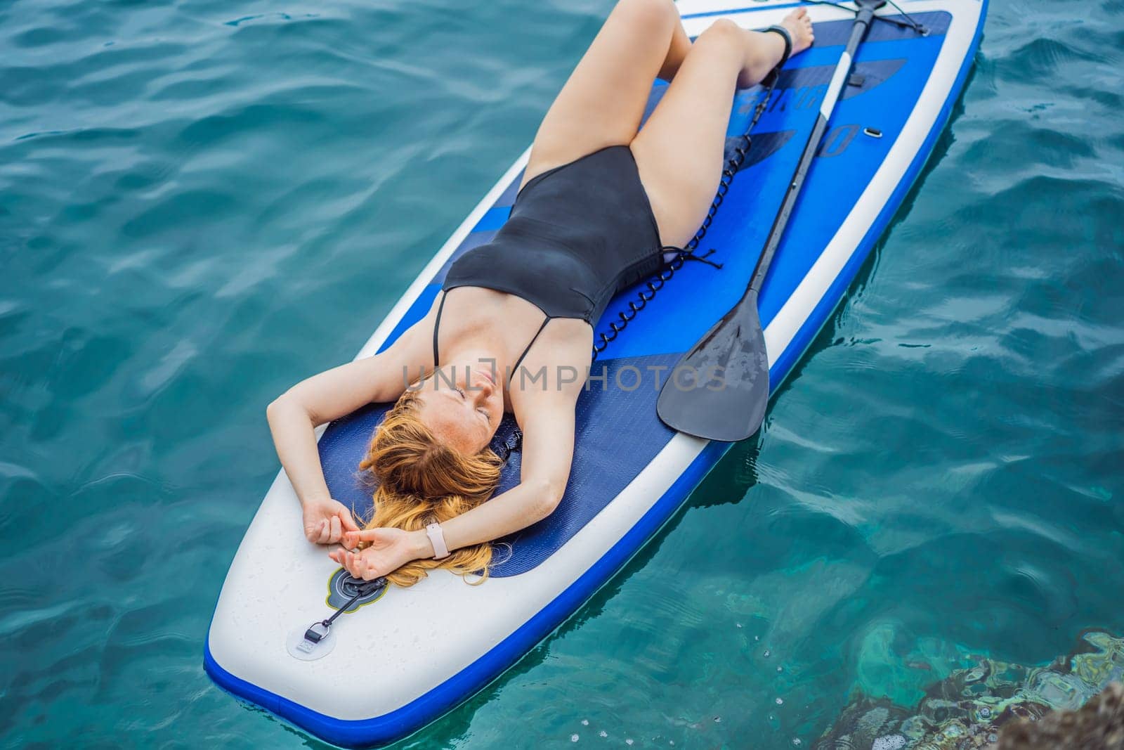 Young women Having Fun Stand Up Paddling in blue water seaamong the rocks in Montenegro. SUP.