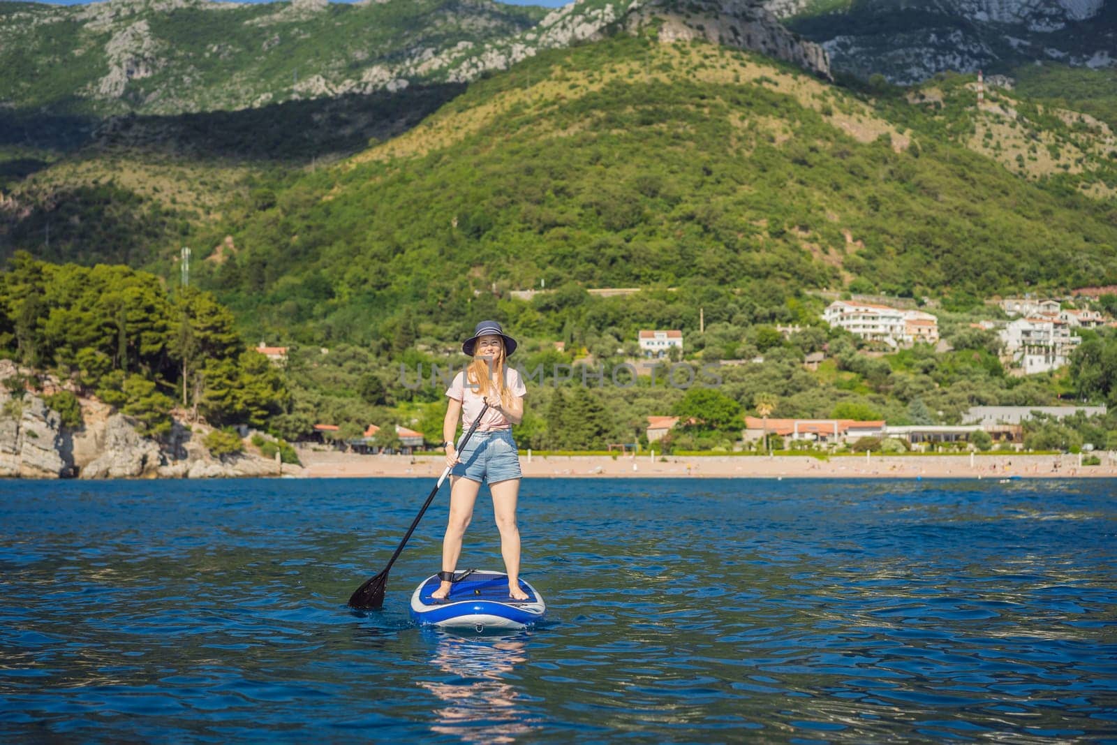 Young women Having Fun Stand Up Paddling in blue water sea near st stefan island in Montenegro. SUP.