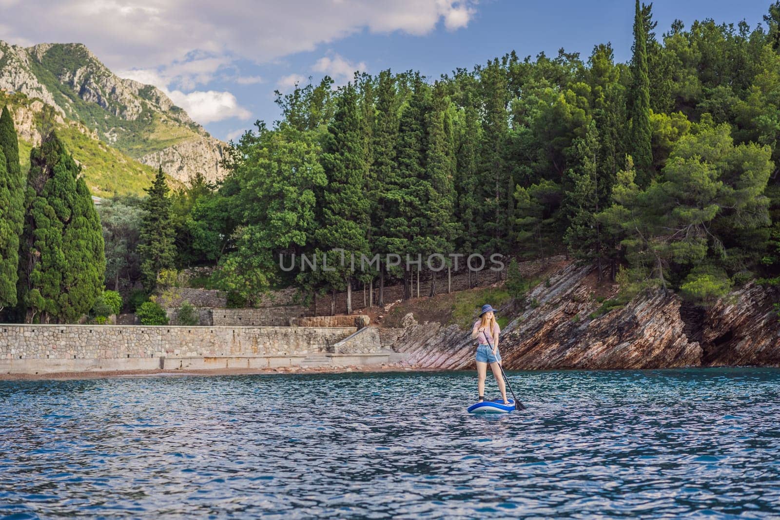 Young women Having Fun Stand Up Paddling in blue water sea near st stefan island against the backdrop of Milocer Park in Montenegro. SUP.
