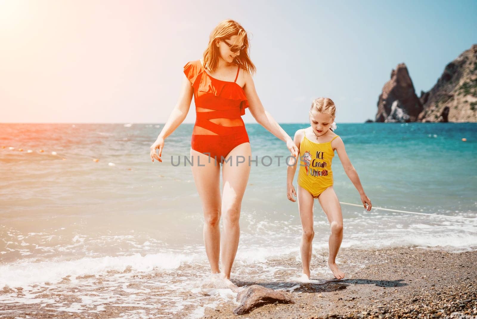 Happy loving family mother and daughter having fun together on the beach. Mum playing with her kid in holiday vacation next to the ocean - Family lifestyle and love concept by panophotograph