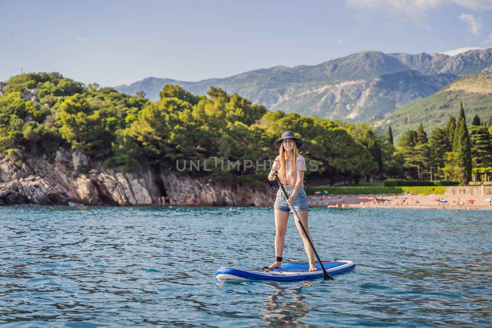 Young women Having Fun Stand Up Paddling in blue water sea near st stefan island against the backdrop of Milocer Park in Montenegro. SUP.