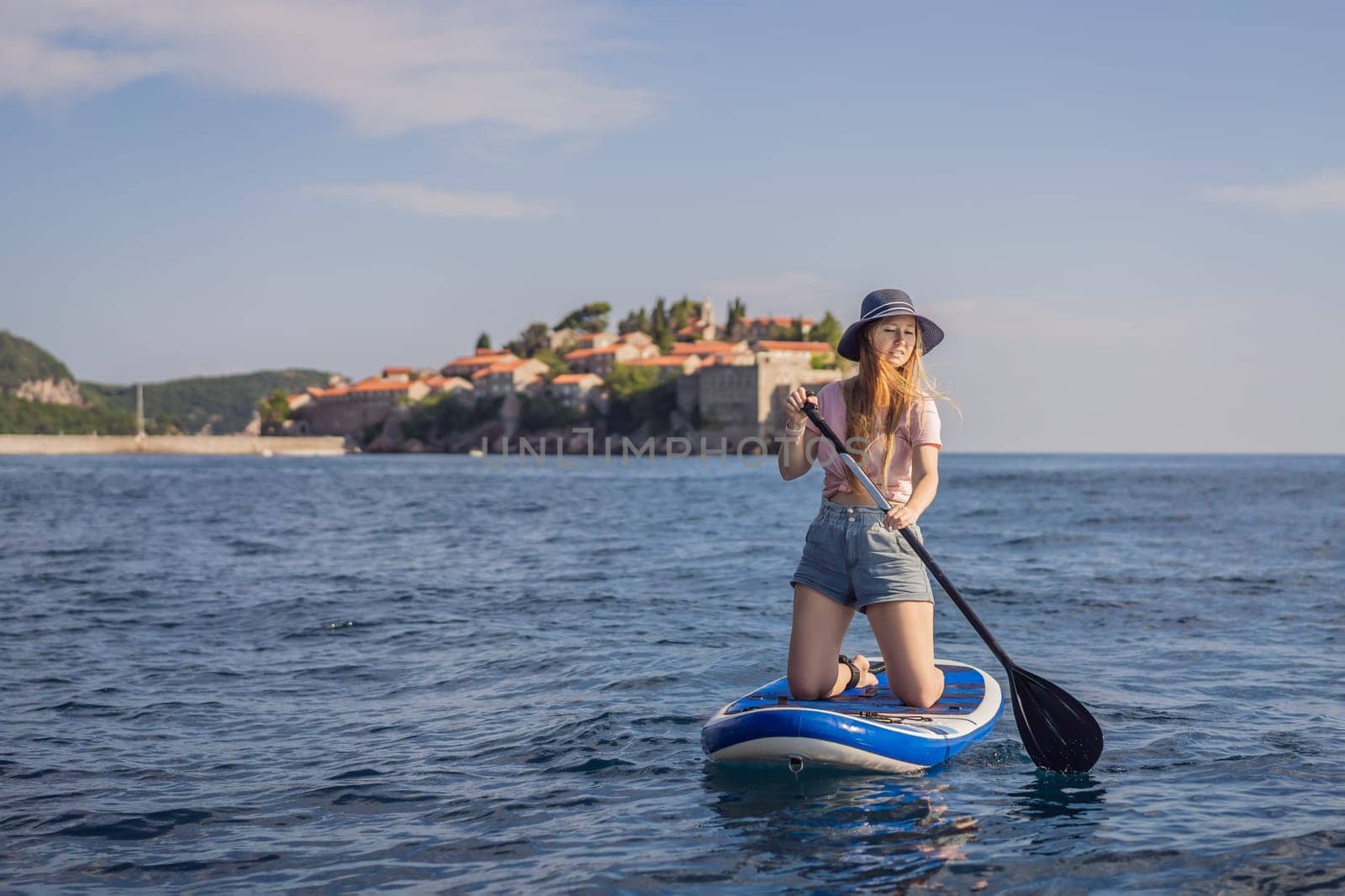 Young women Having Fun Stand Up Paddling in blue water sea near st stefan island in Montenegro. SUP.