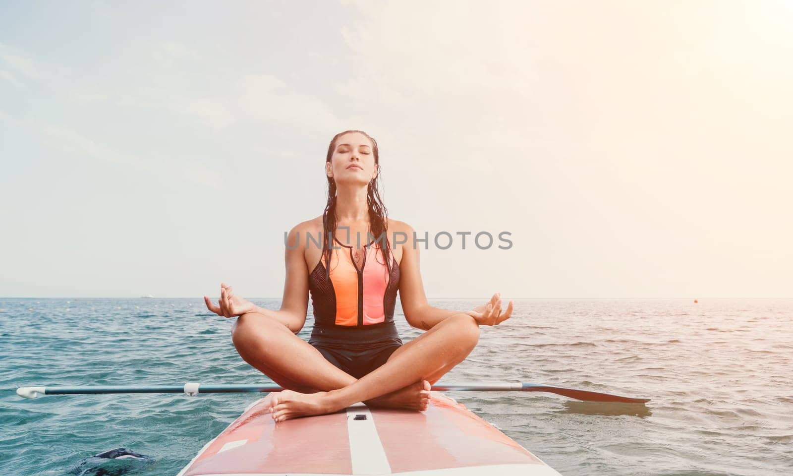 Woman sup yoga. Happy young sporty woman practising yoga pilates on paddle sup surfboard. Female stretching doing workout on sea water. Modern individual female outdoor summer sport activity