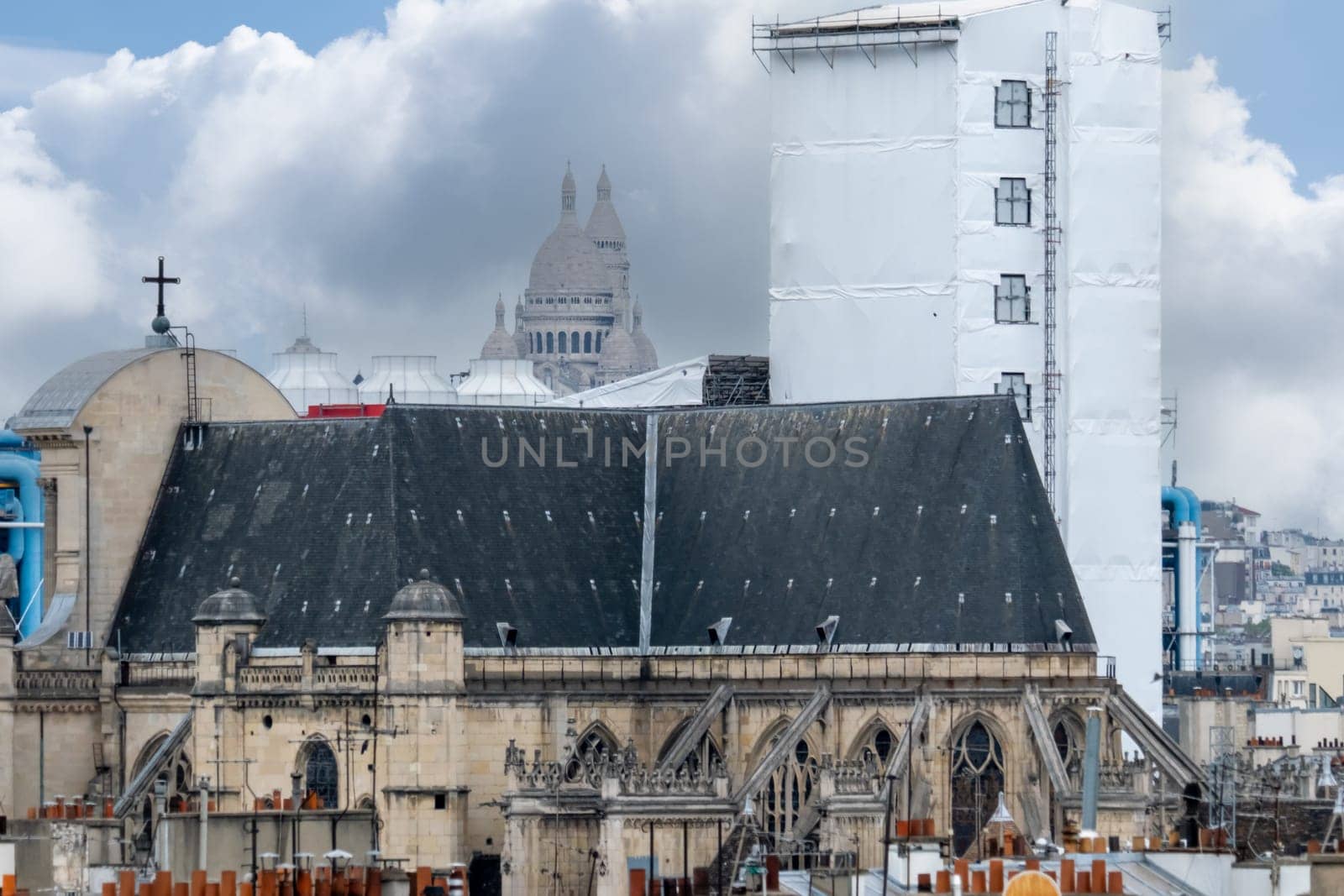 6 May 2023. Paris, France. Rooftop view of Paris preparing for the 2024 Olympics by remodeling, new construction. Telephoto shot with Sacre Coeur in the distance, church Saint Gervais and parts of Pompidou center in the foreground.