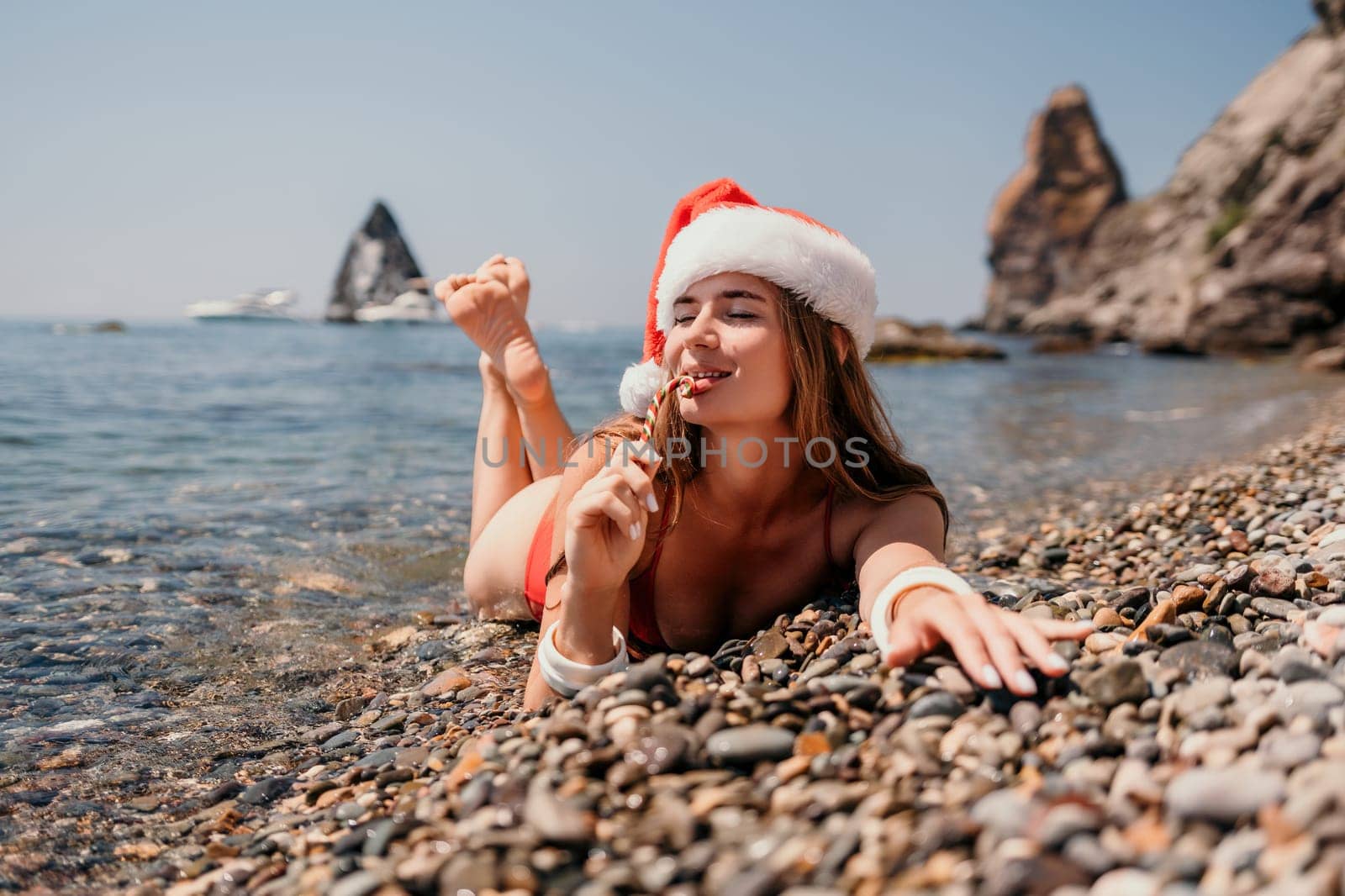 Woman travel sea. Happy tourist enjoy taking picture on the beach for memories. Woman traveler in Santa hat looks at camera on the sea bay, sharing travel adventure journey by panophotograph