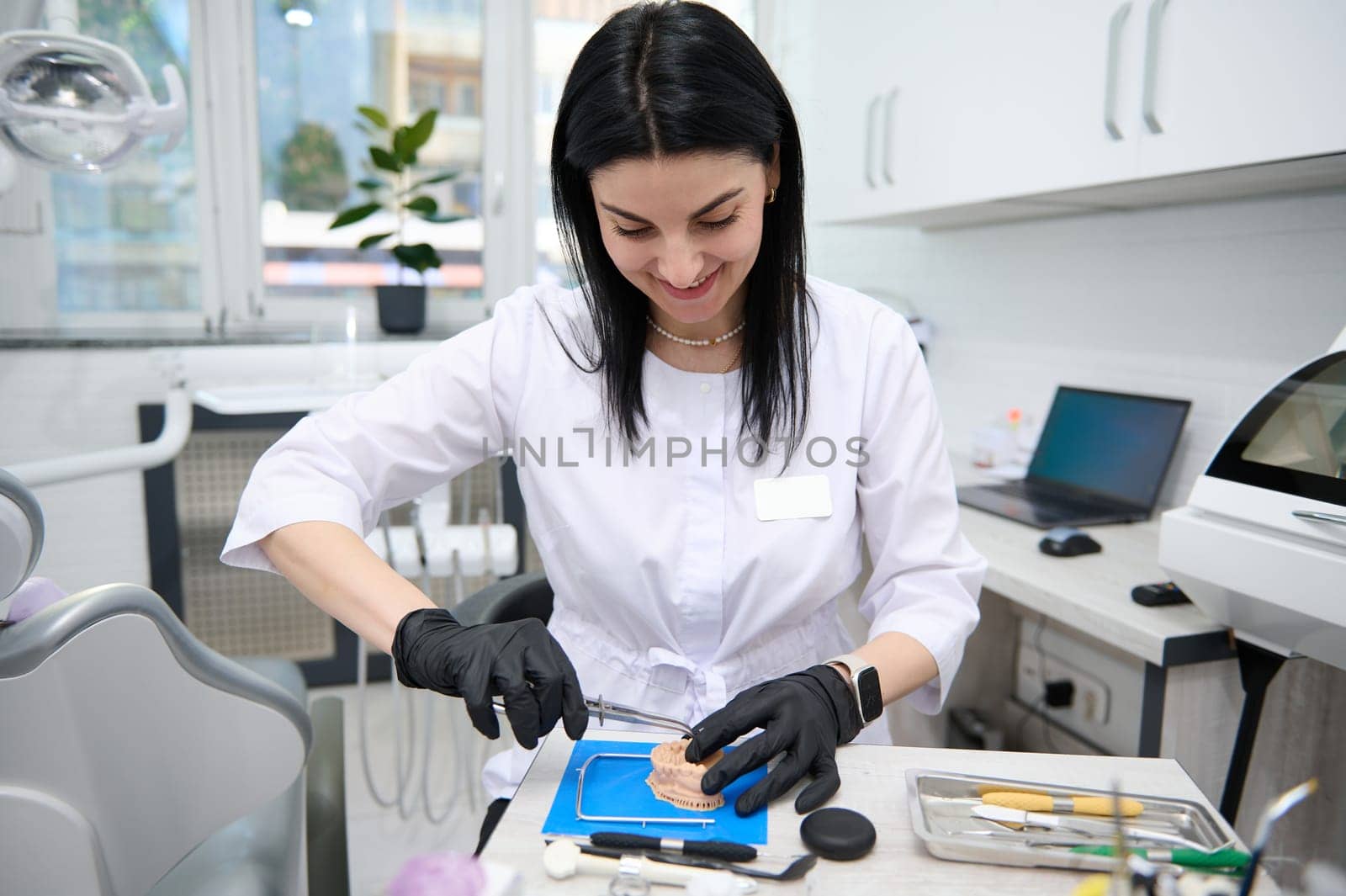 Portrait of a confident experienced woman dentist doctor, dental technician, prosthetic engineer enjoying his professional occupation, working with dental prosthesis in dentistry clinic. Orthodontics.