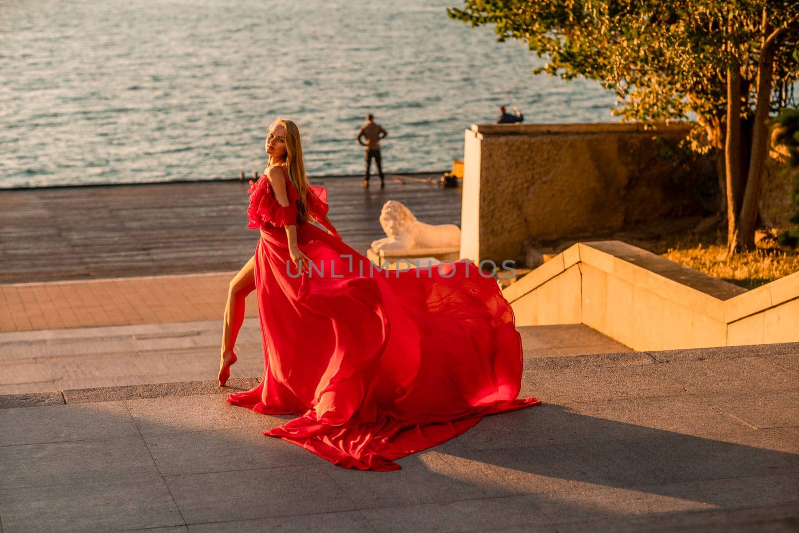 Sunrise red dress. A woman in a long red dress against the backdrop of sunrise, bright golden light of the sun's rays. The concept of femininity, harmony. by Matiunina