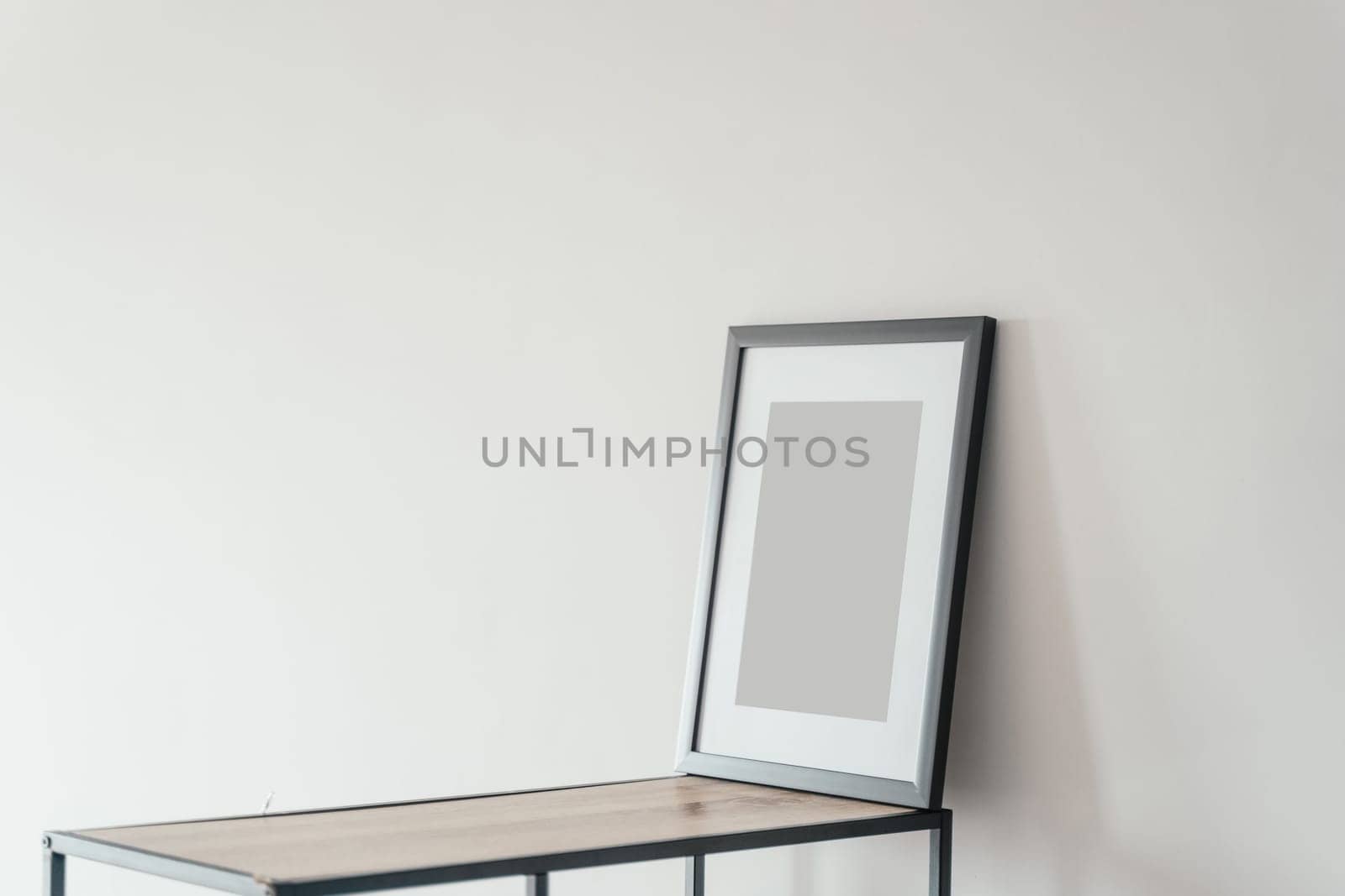 Blank wooden photo frame stands in the interior on a white background. Mockup by driver-s