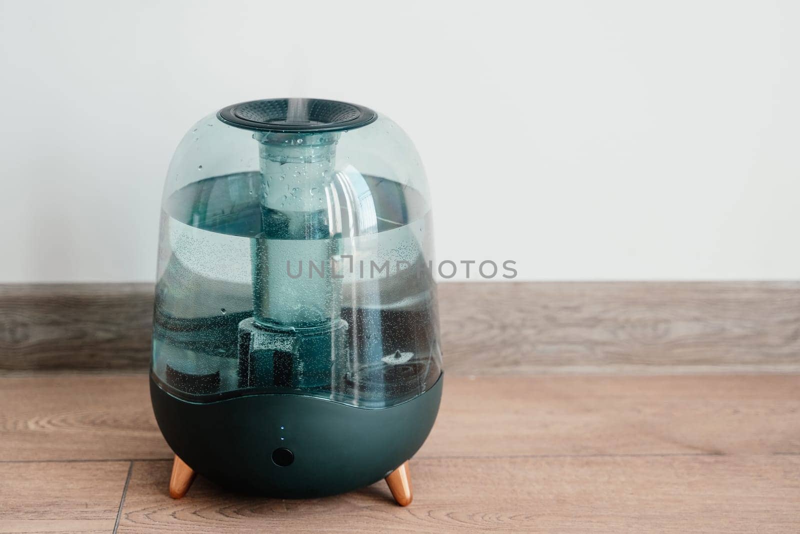 Modern air humidifier on a white wall background. Humidifier spreading steam into the living room.