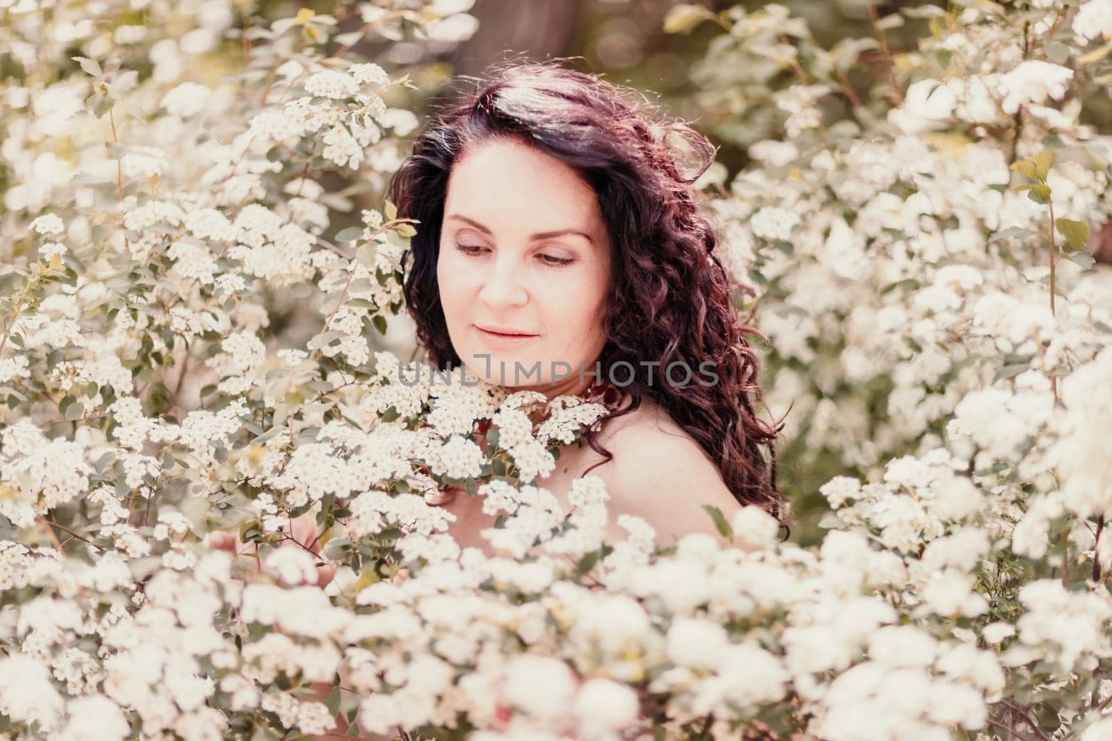 Woman spirea flowers. Portrait of a curly happy woman in a flowering bush with white spirea flowers. by Matiunina