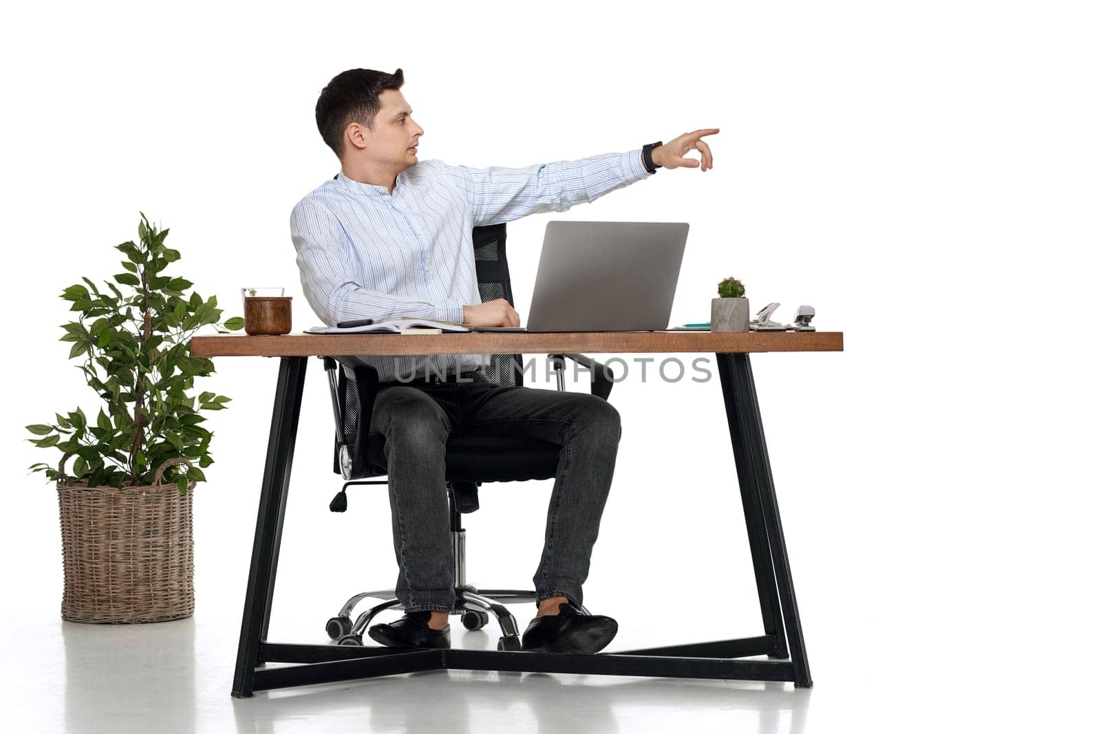 young man using laptop at table and pointing at copy space by erstudio