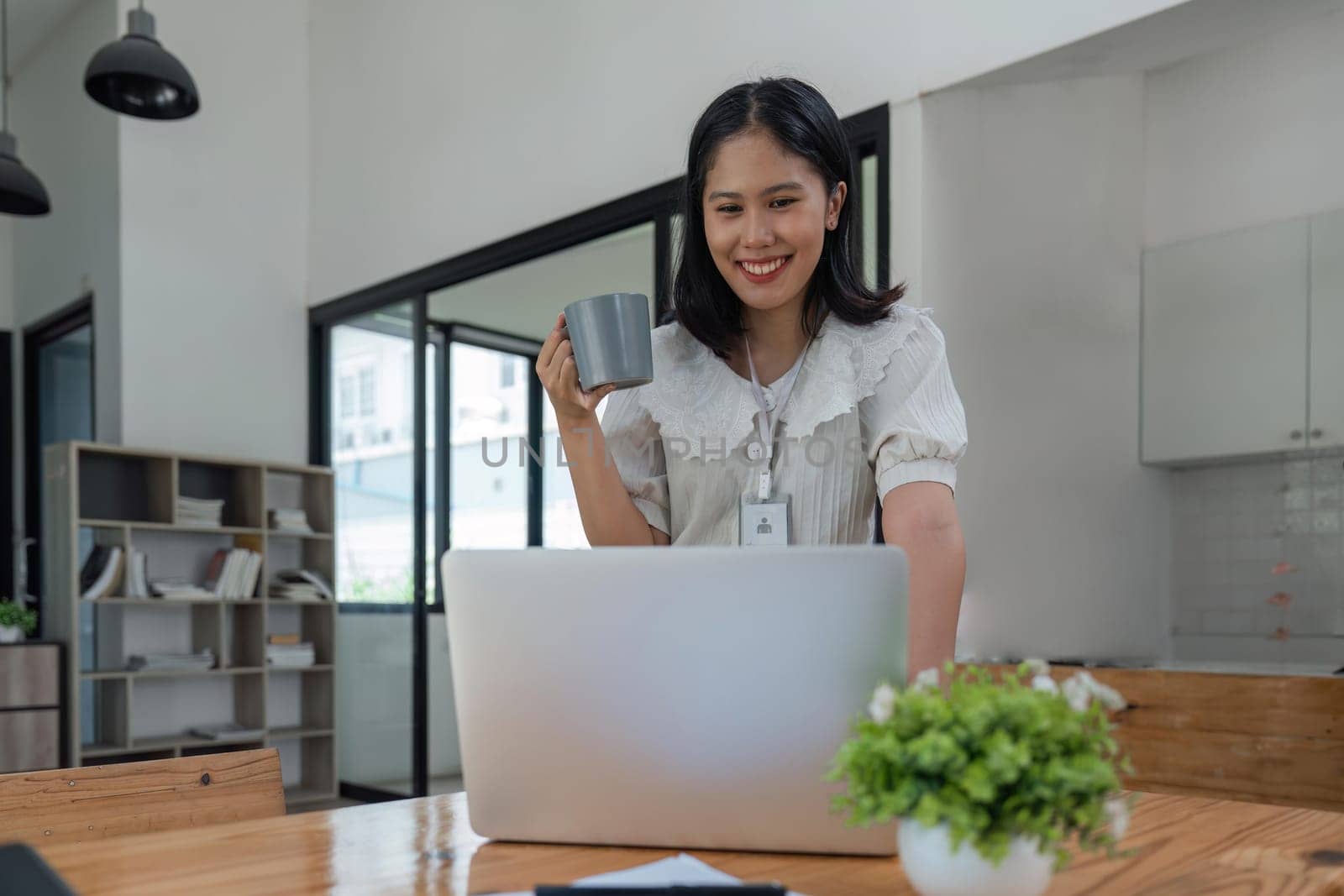 Cheerful business lady working on laptop in office, Asian happy beautiful businesswoman work in workplace. Attractive female employee office worker smile.