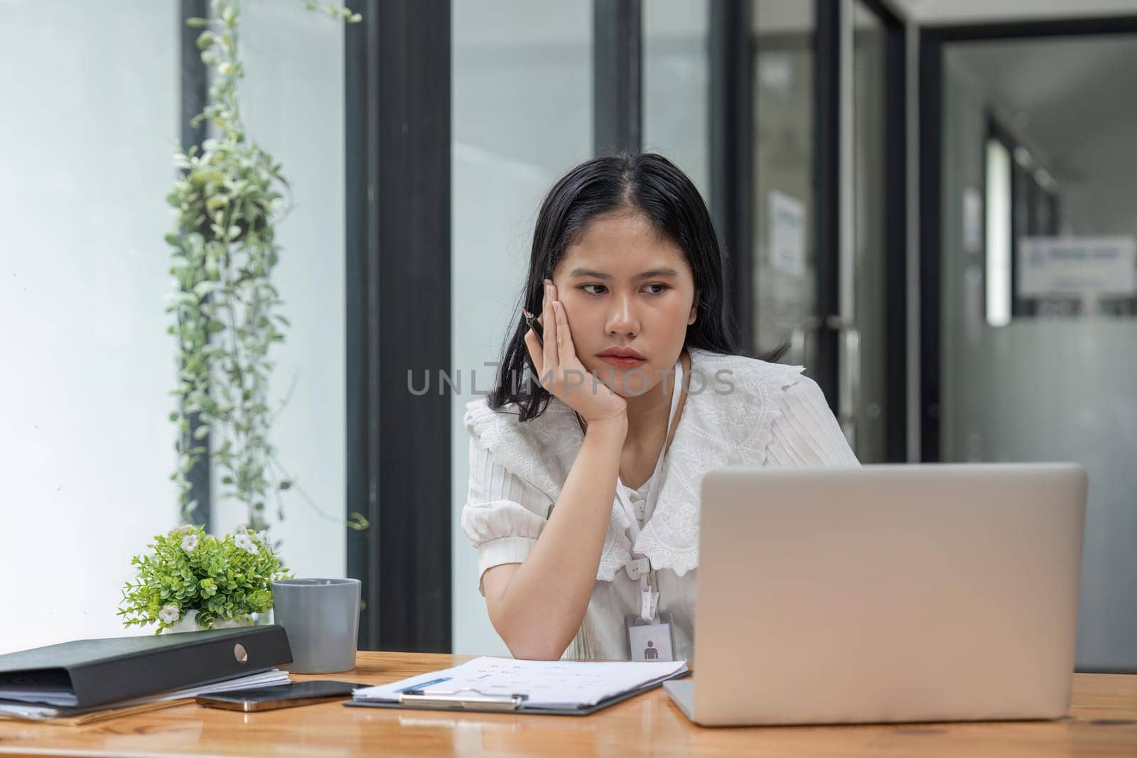 Beautiful Business woman sit in front of her laptop with the stressful face and headache from her works.She sits in modern office analyzing.