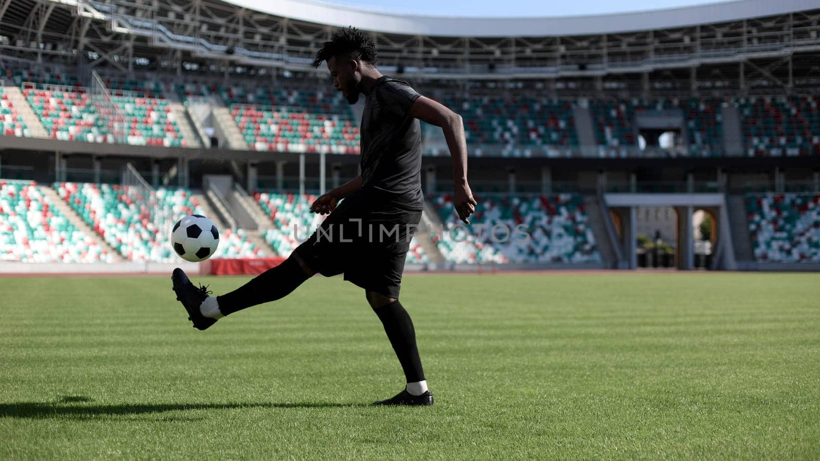 African American man playing football on the stadium field.