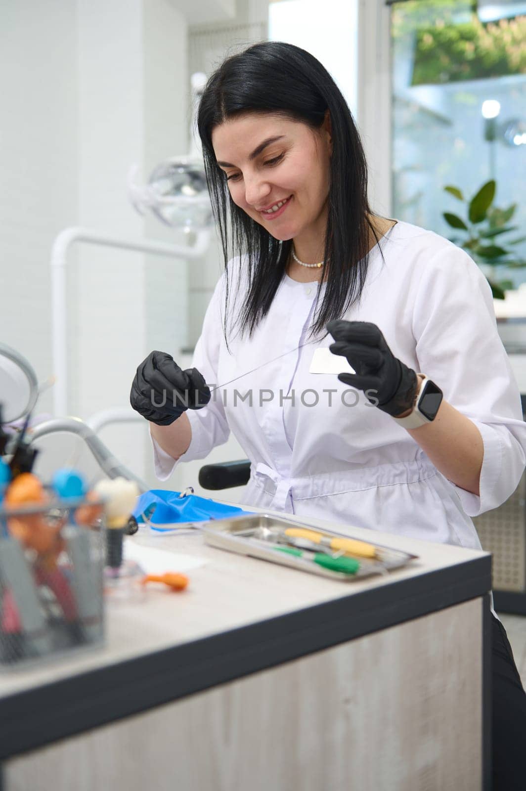 Portrait of Caucasian confident smiling woman dentist doctor working in dental office, dressed in white medical uniform and black sterile gloves. People. Profession. Healthcare worker. Medical staff