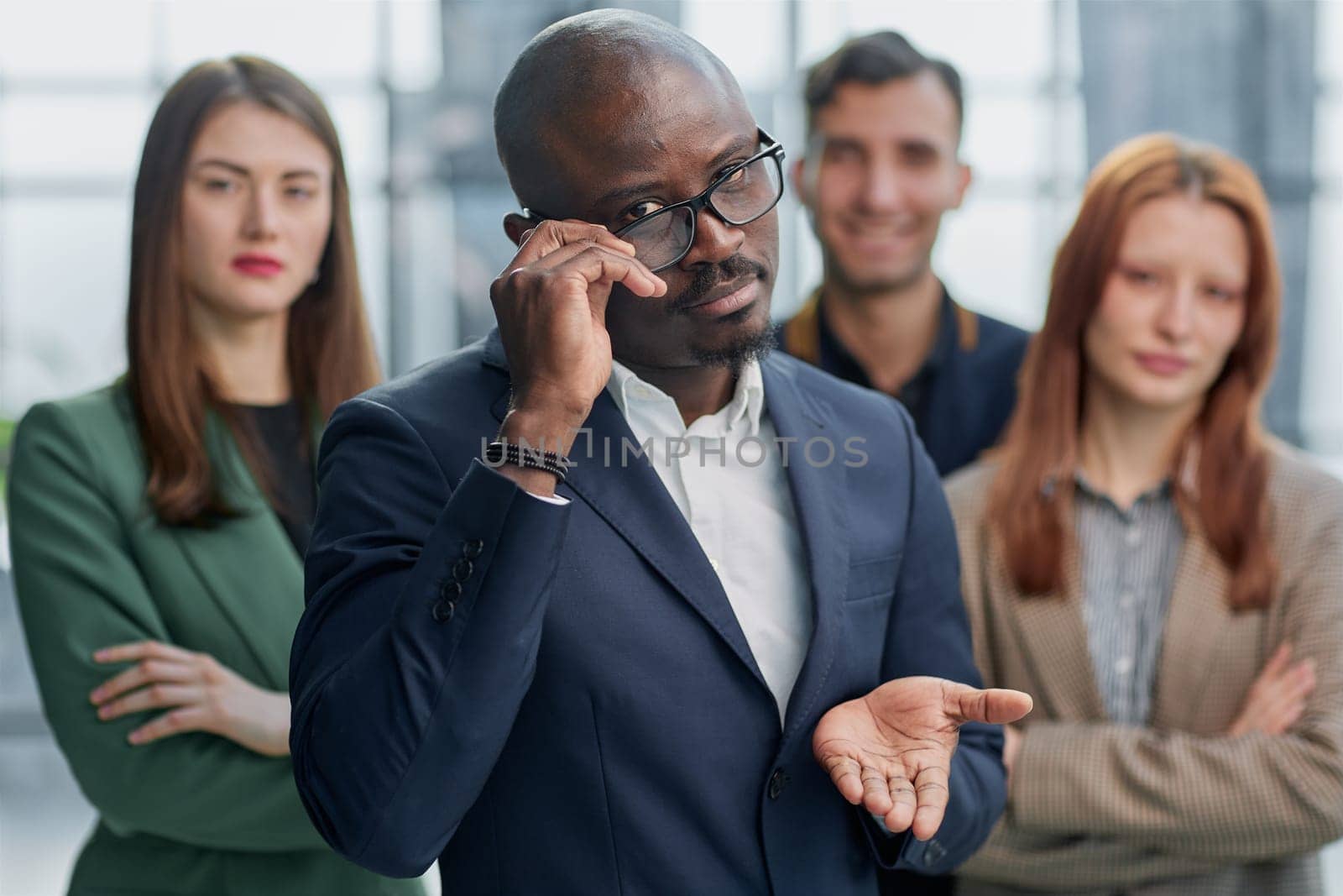 Modern young businessman in formal wear adjusting glasses looking at camera while standing in office