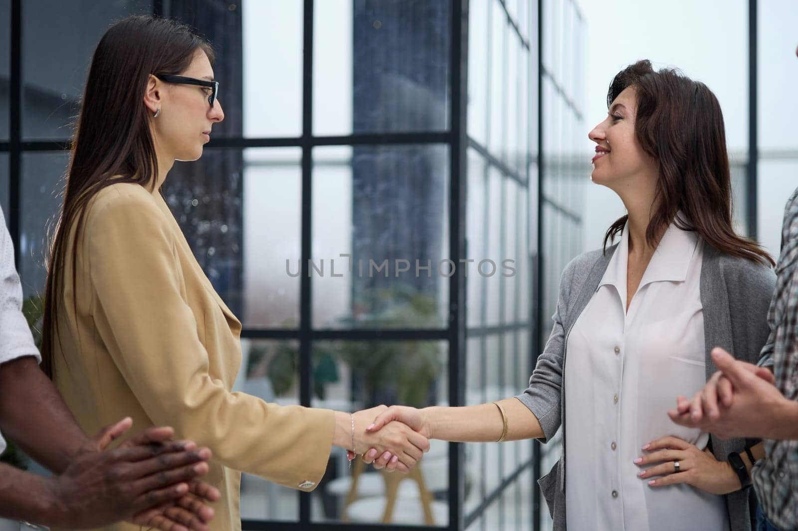 Two professional business people shaking hands in an office lobby by Prosto