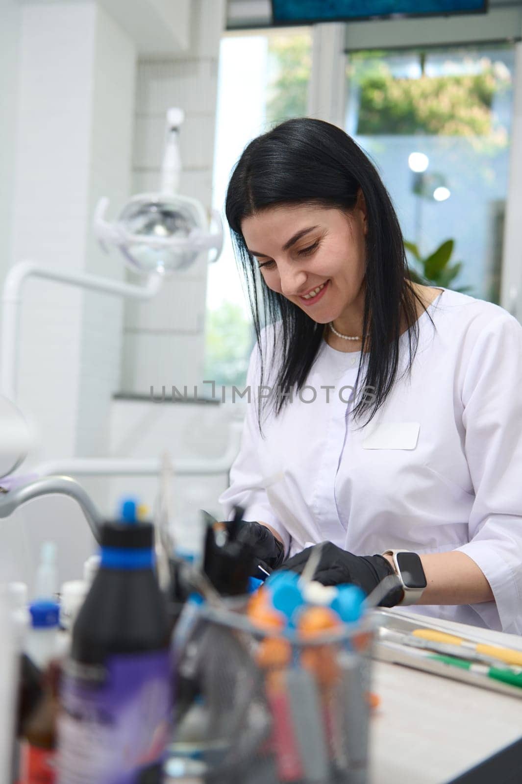 Beautiful smiling happy woman 30s, professional dentist, experienced dental technician, prosthetic engineer working with gypsum mold of human jaw in dental medical lab. Orthodontics. Dentistry