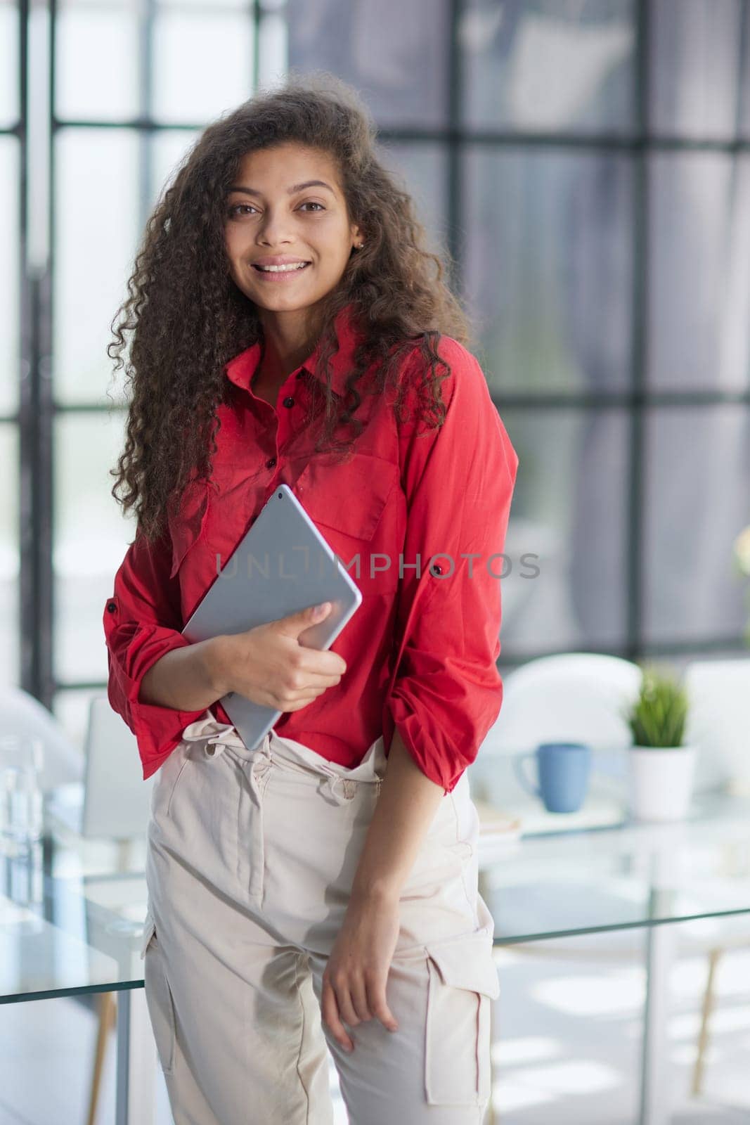 Happy woman manager holding tablet and standing in modern office by Prosto