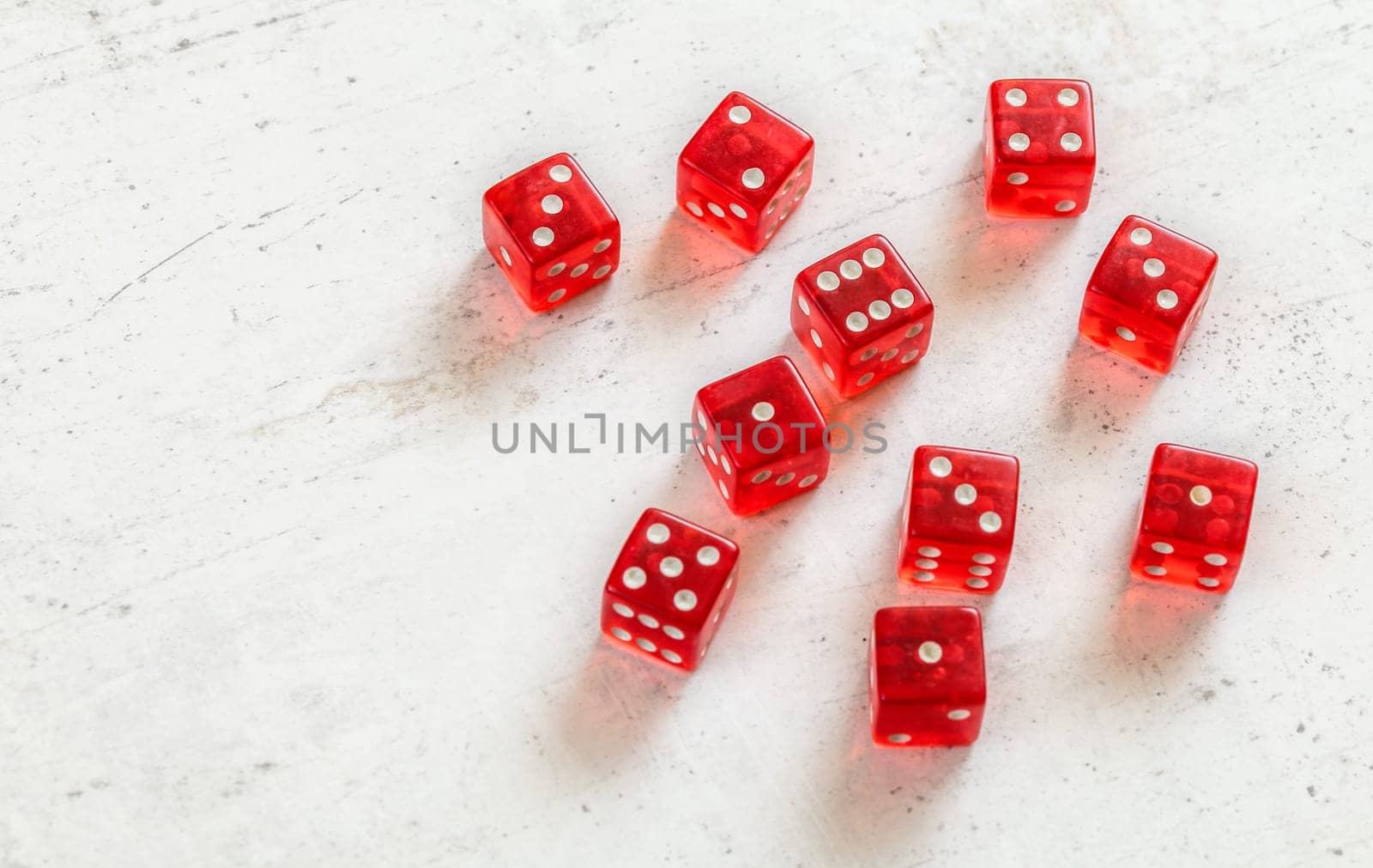 Ten red transcluent craps dices showing different numbers on white marble board, space for text left side.