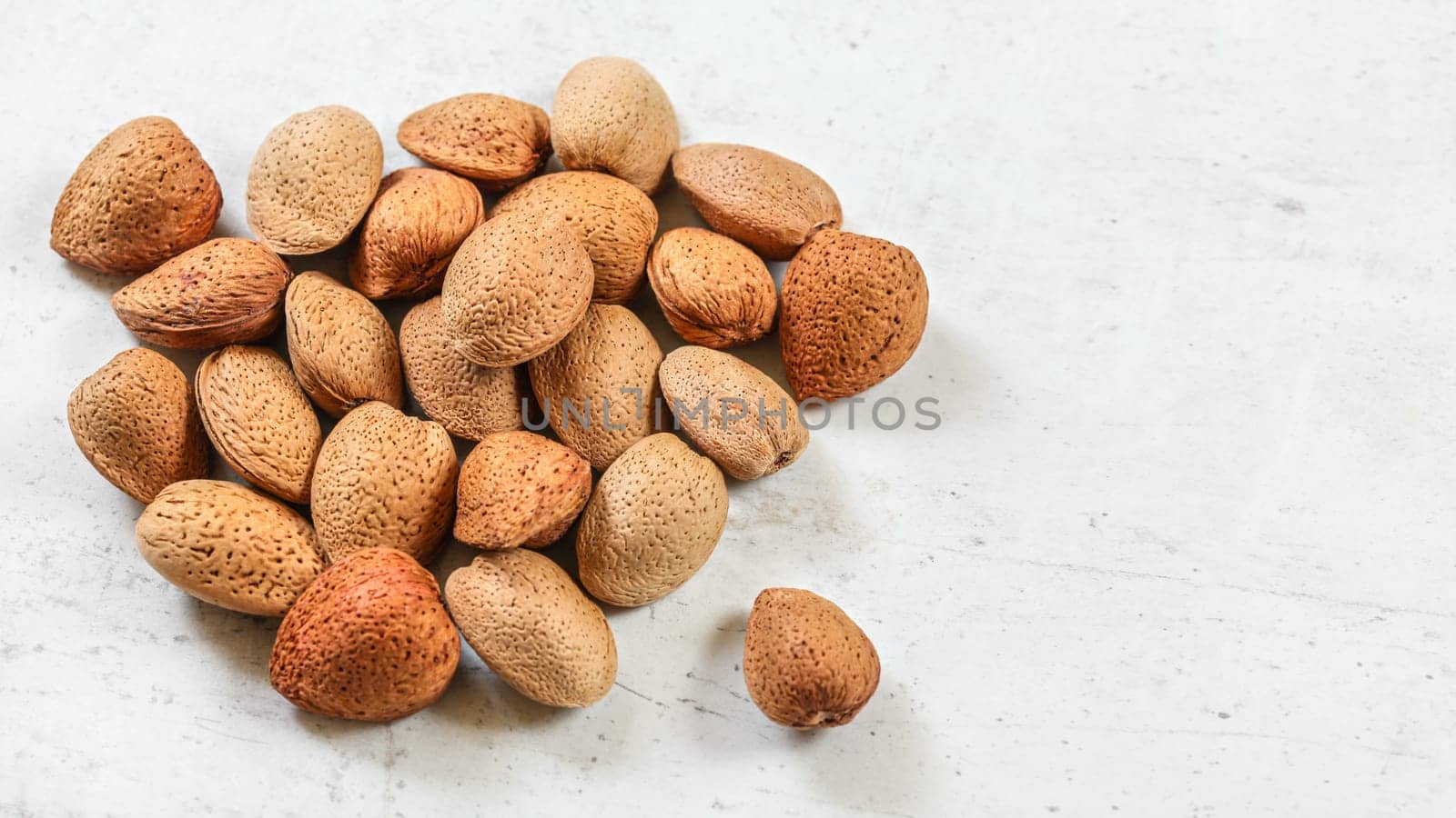 Whole almonds in shell, on white board.