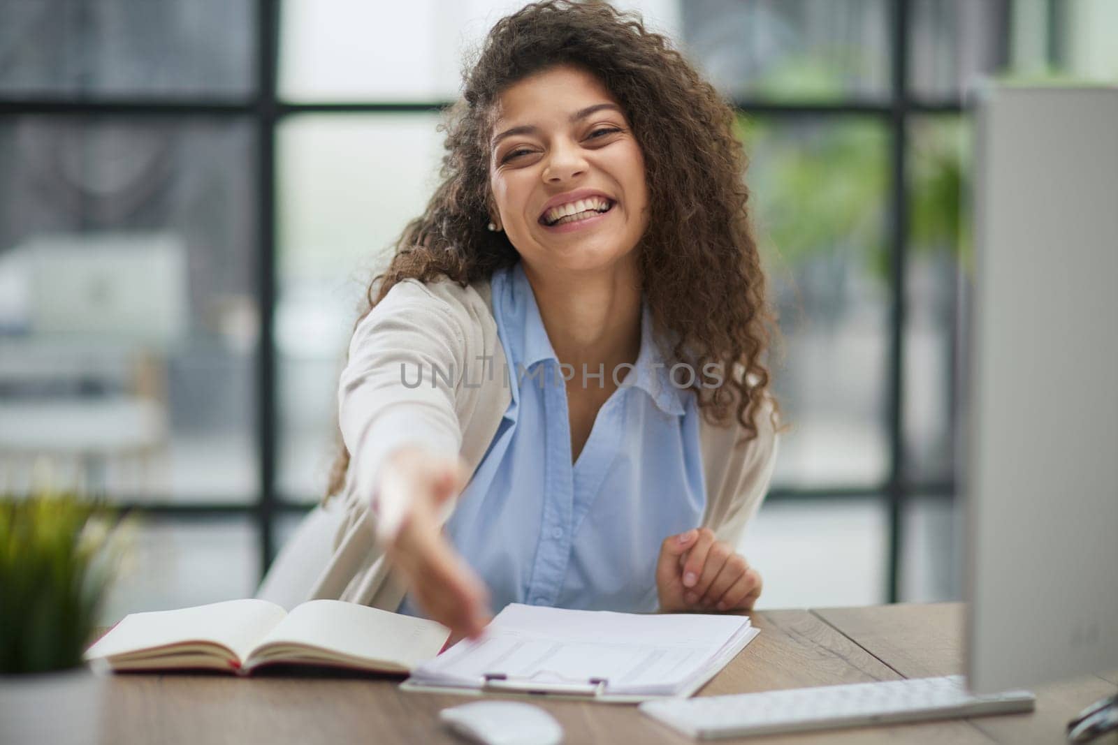 Happy young woman looking at the camera while welcoming a client. Smiling female executive manager, secretary offering professional business services