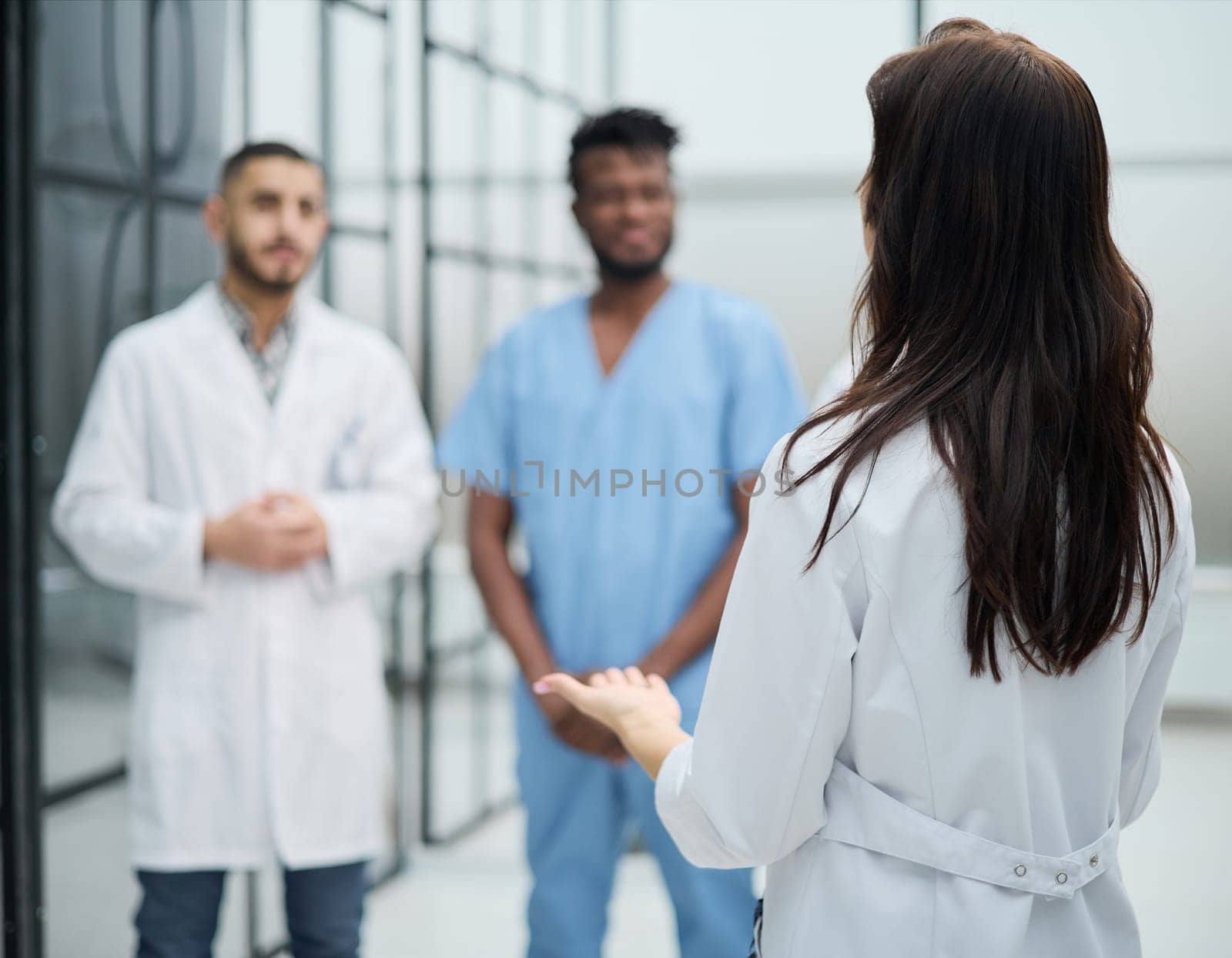 medic woman stands with her back and instructs with colleagues in the hospital