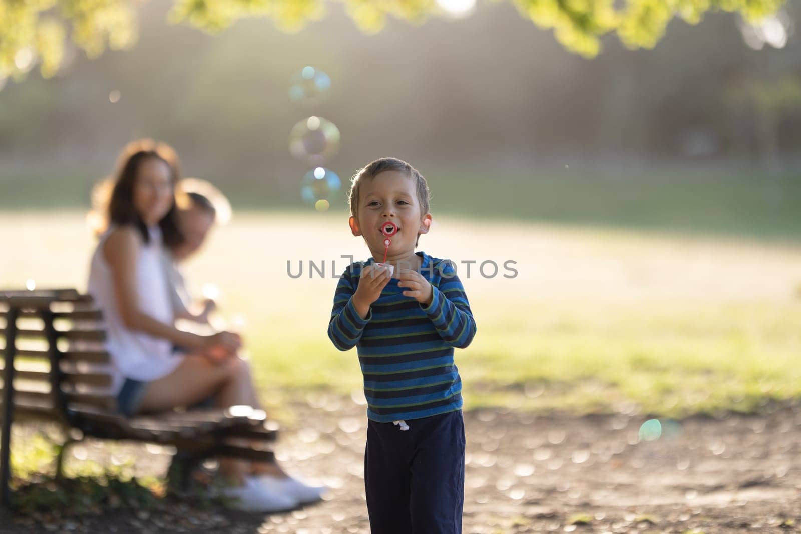 Cute little boy blowing soap bubbles. Mid shot