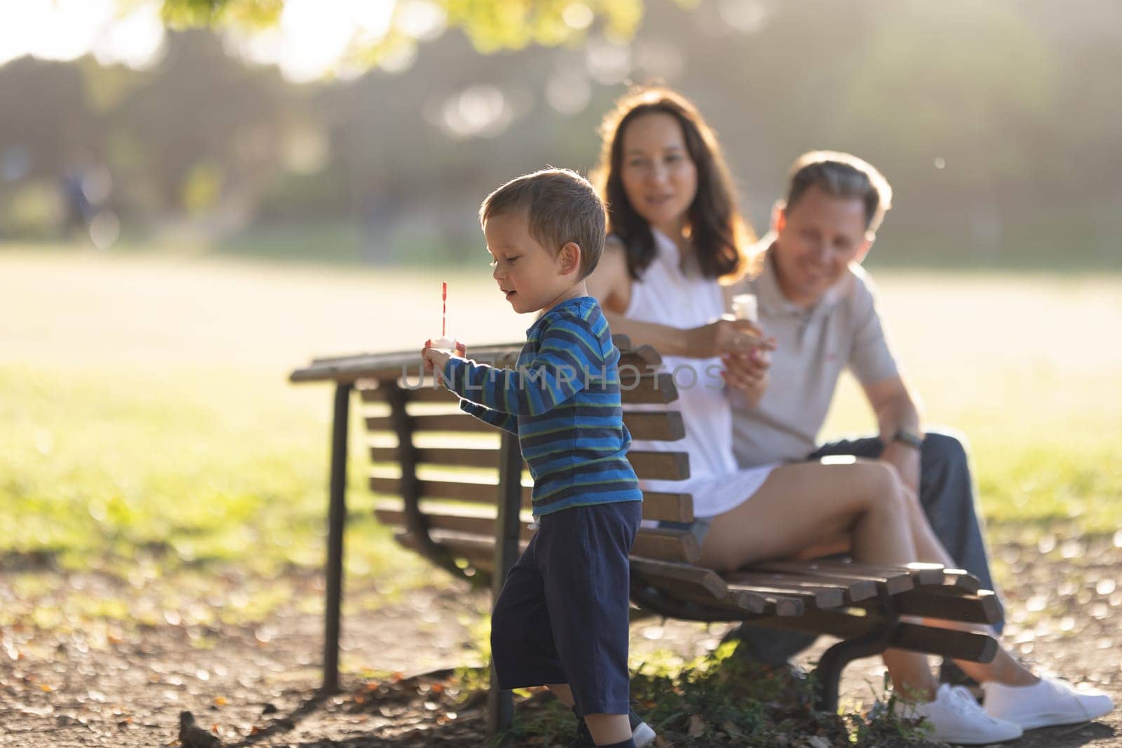 Family in the park - cute little boy blowing soap bubbles by Studia72
