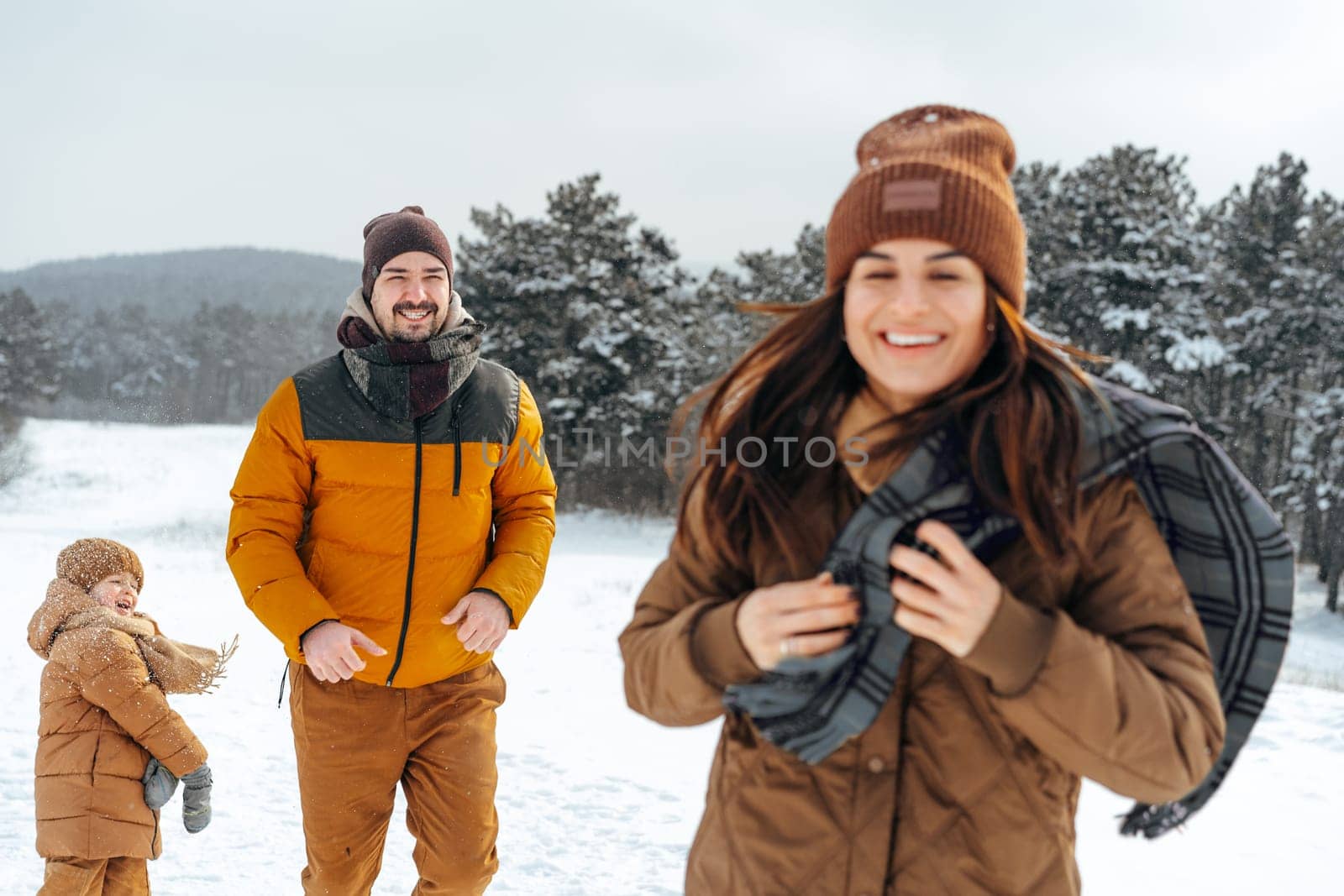 Happy family having a walk in winter outdoors in snow forest