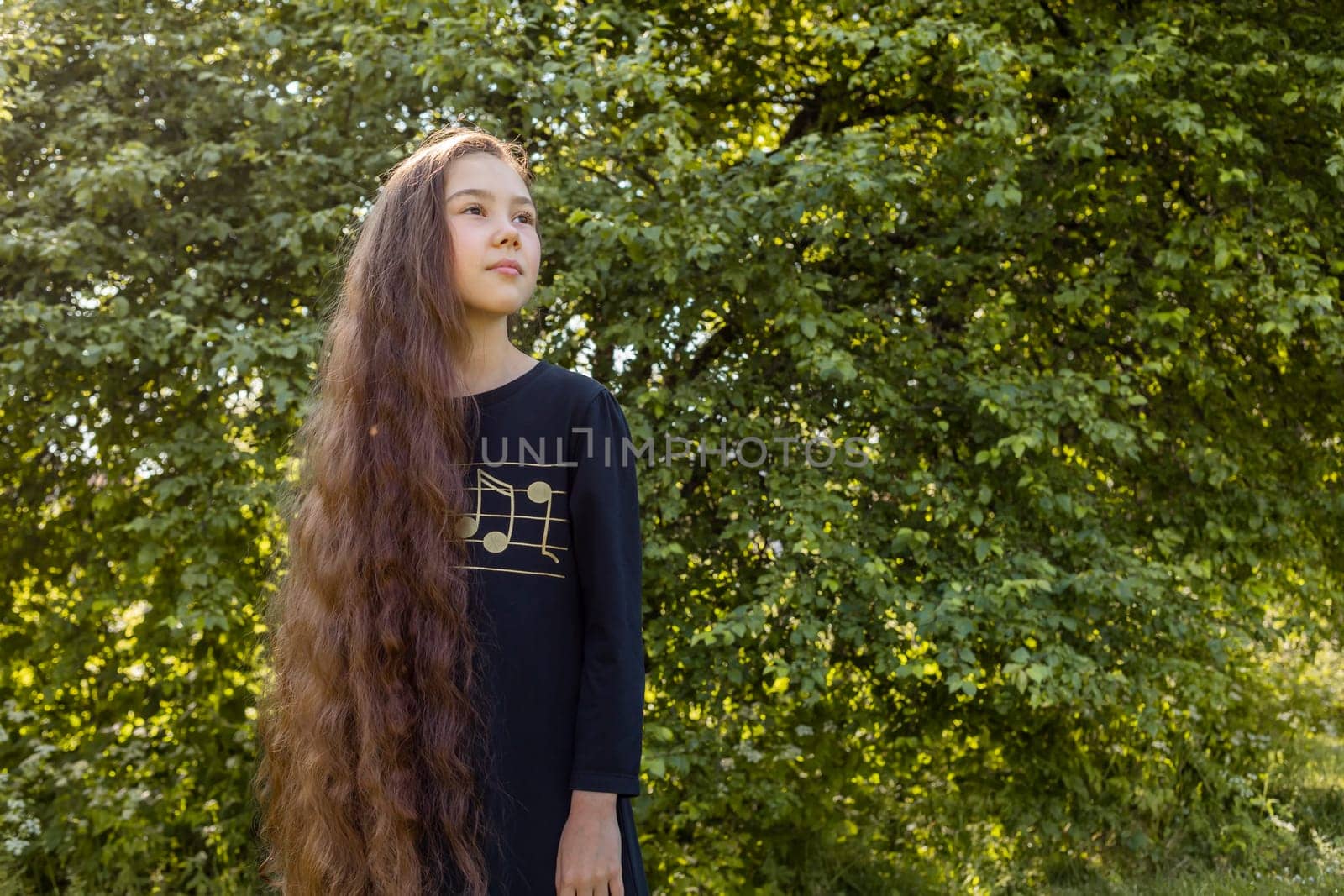 Little Adorable Girl With Long Shiny Smooth Hair Posing in Meadow. Caucasian Asian Brown Haired Child Having Fun, Enjoying Nature. Carefree, Happy Childhood, Hair Growth. Copyspace, Horizontal Plane.
