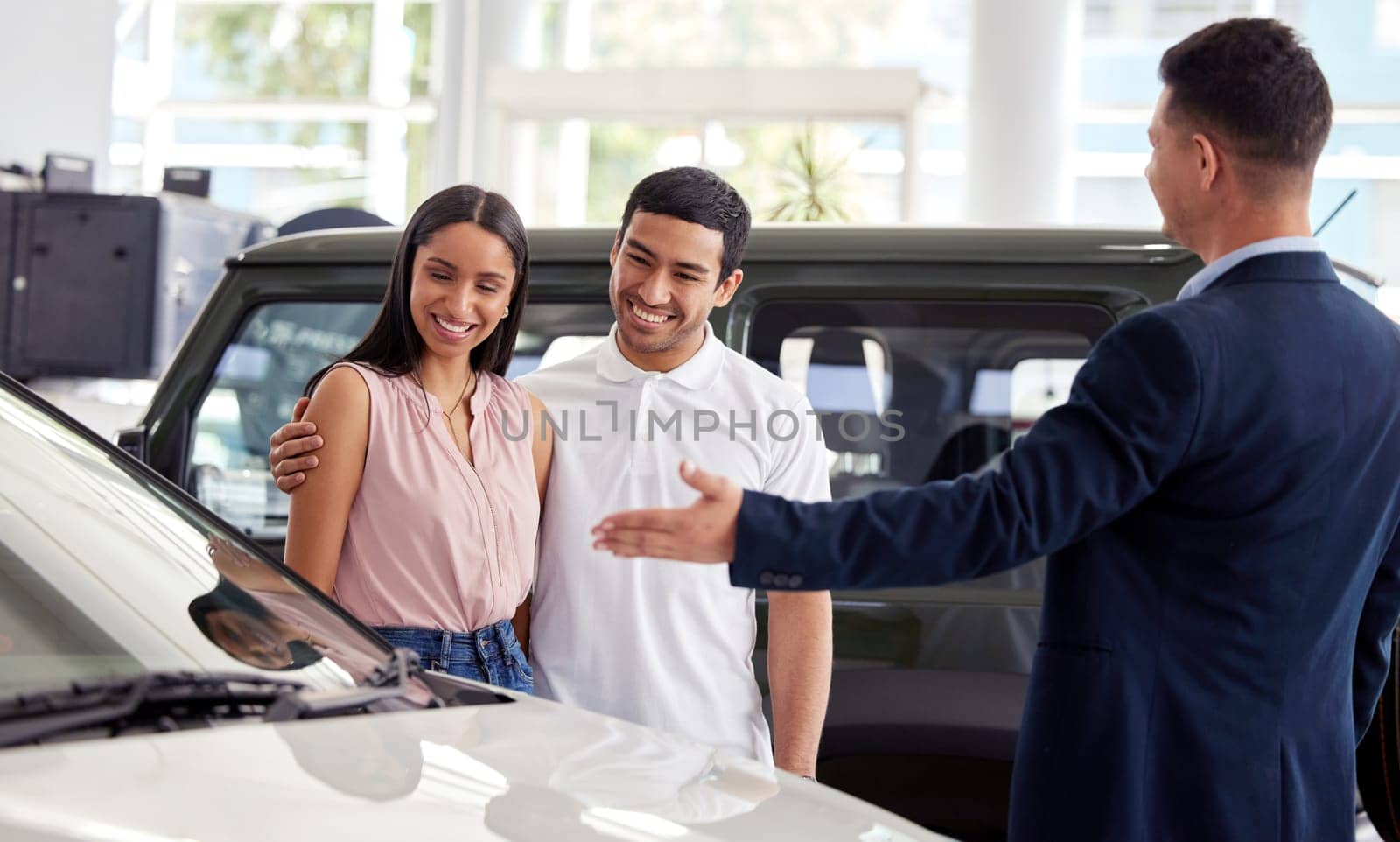 Couple at car dealership, choice and transportation with salesman, customer buying new transport with luxury. Sales, agreement and show cars with people at automobile showroom with purchase decision.