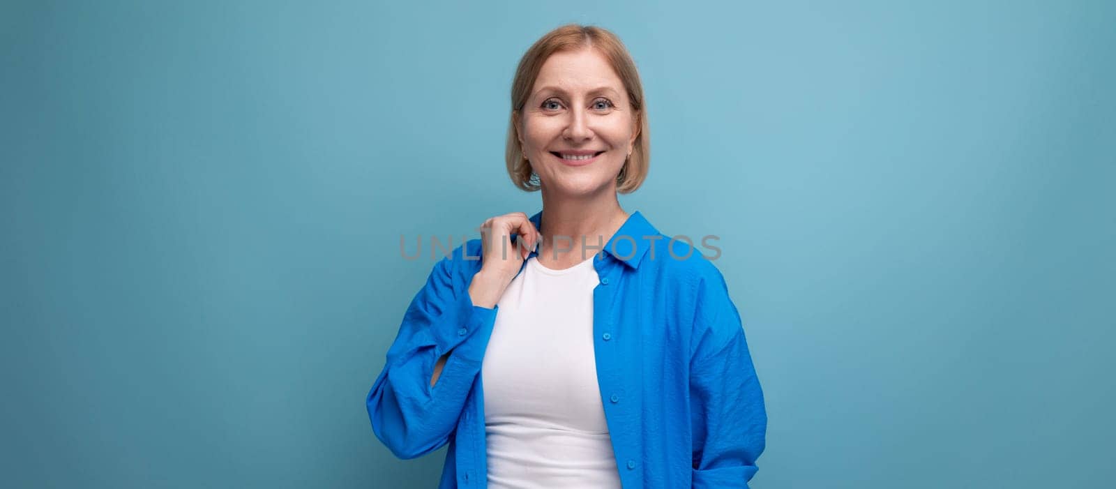 smiling mature woman thinking brilliant idea on blue background with copyspace.