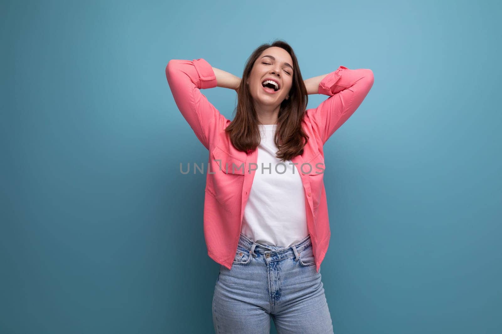 happy lucky brunette woman in informal look rejoices on studio background by TRMK