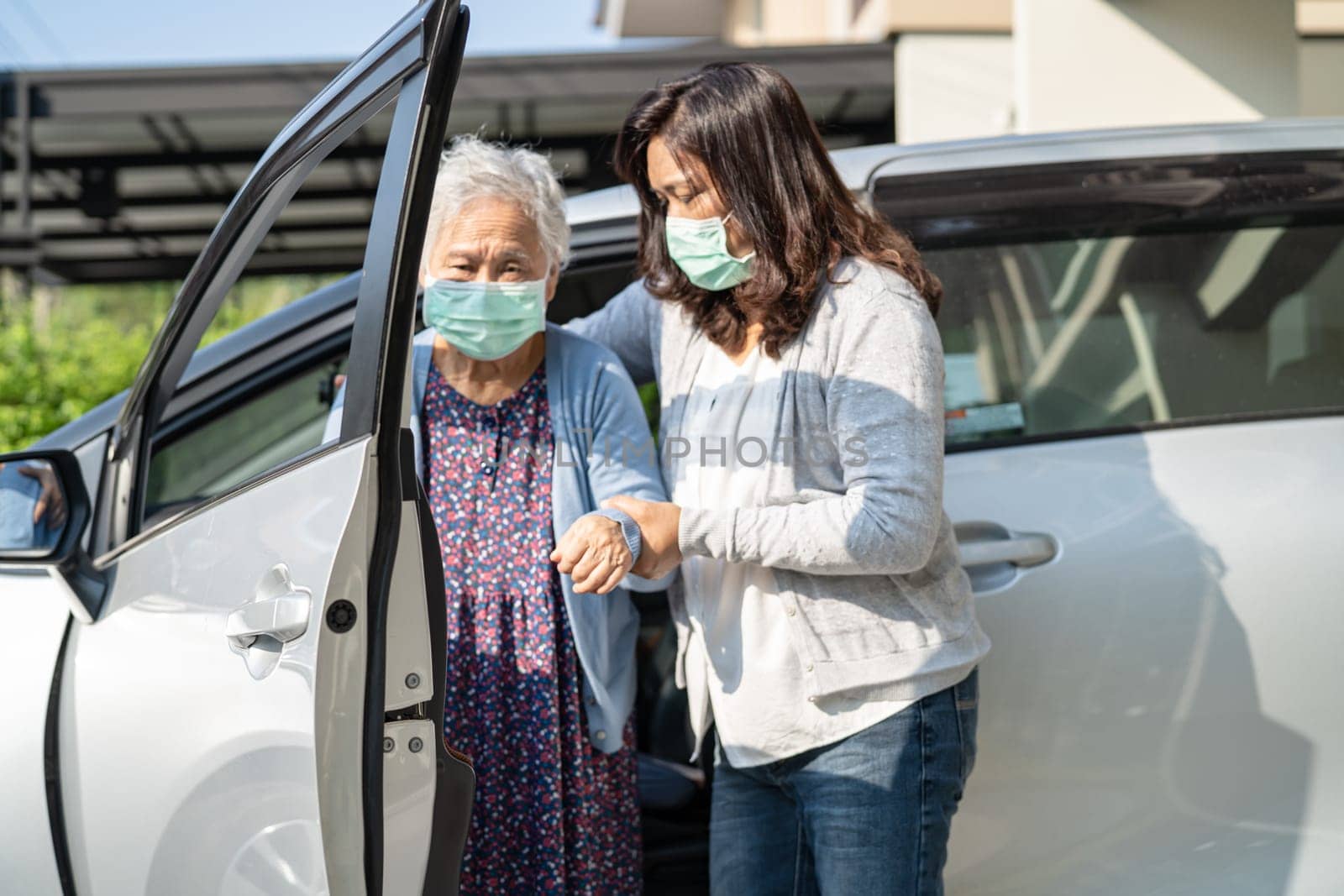 Caregiver help and support asian elderly woman sitting on wheelchair prepare get to her car to travel in holiday.