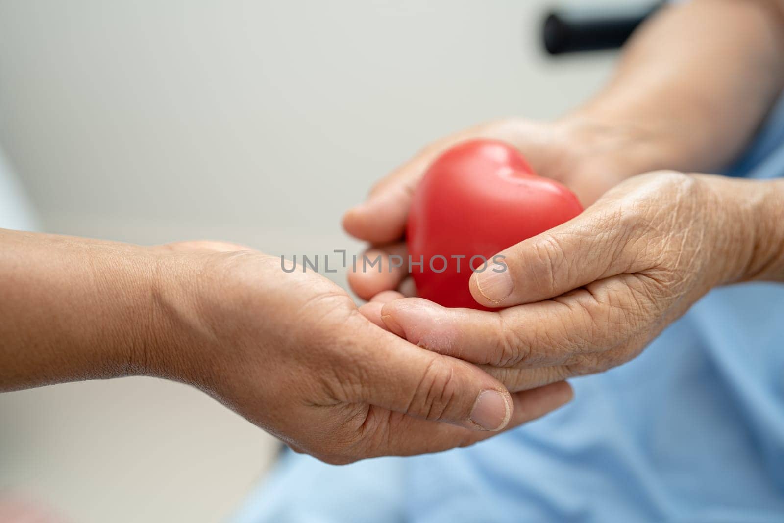 Asian senior holding a red heart in hospital, healthy strong medical concept. by pamai