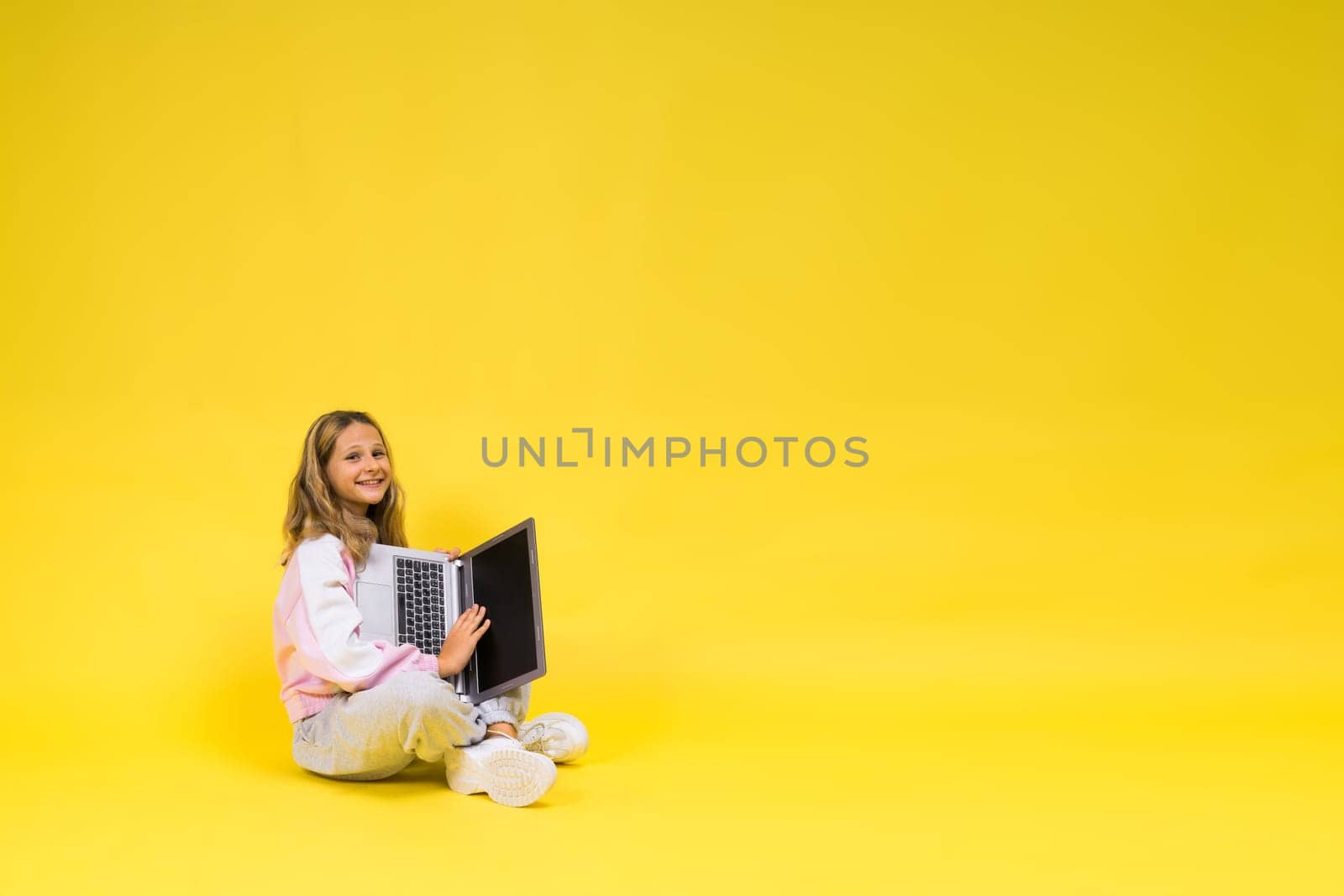 Teenager girl with notebok computer laptop sitting in a studio