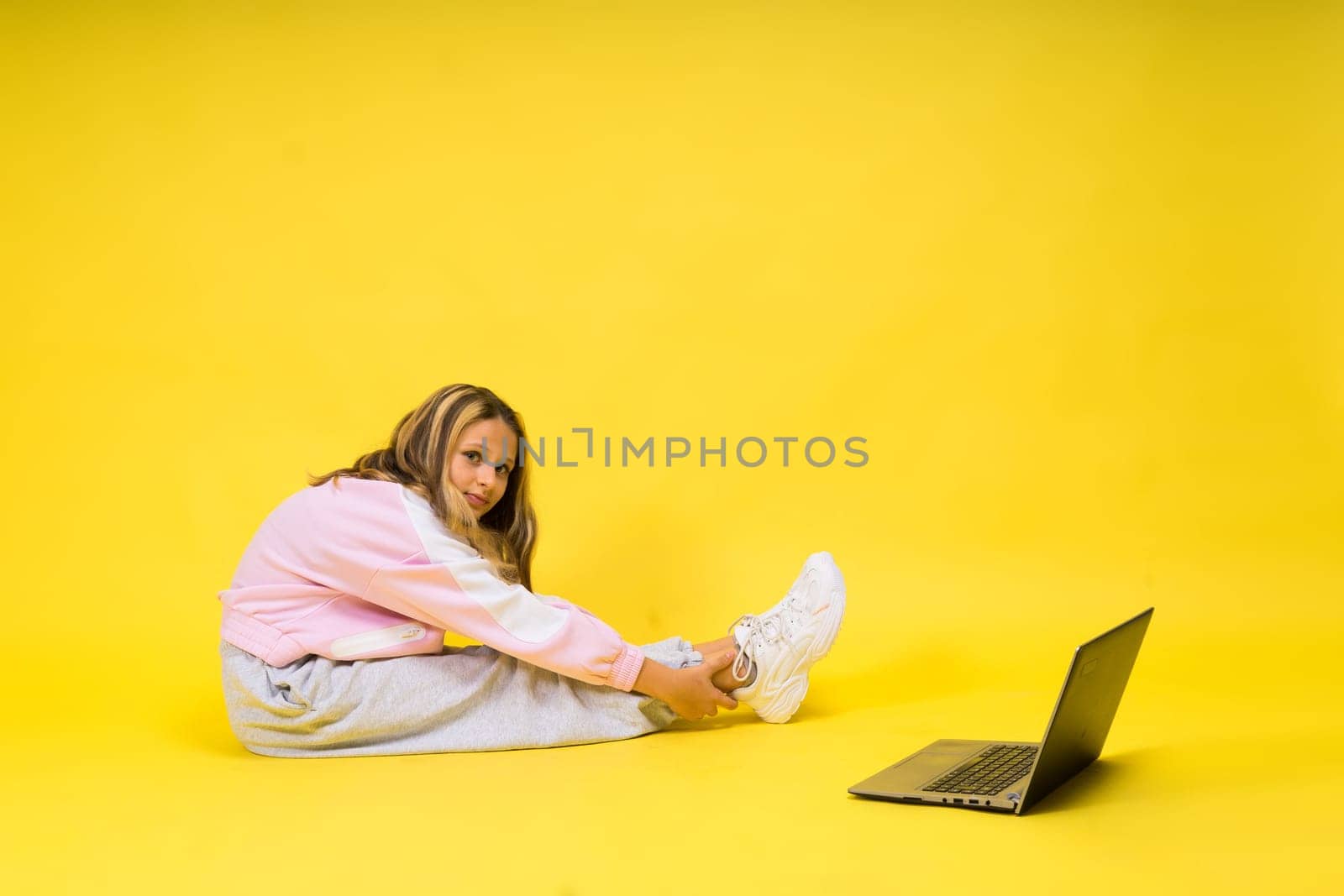 Teenager girl with notebok computer laptop sitting in studio by Zelenin