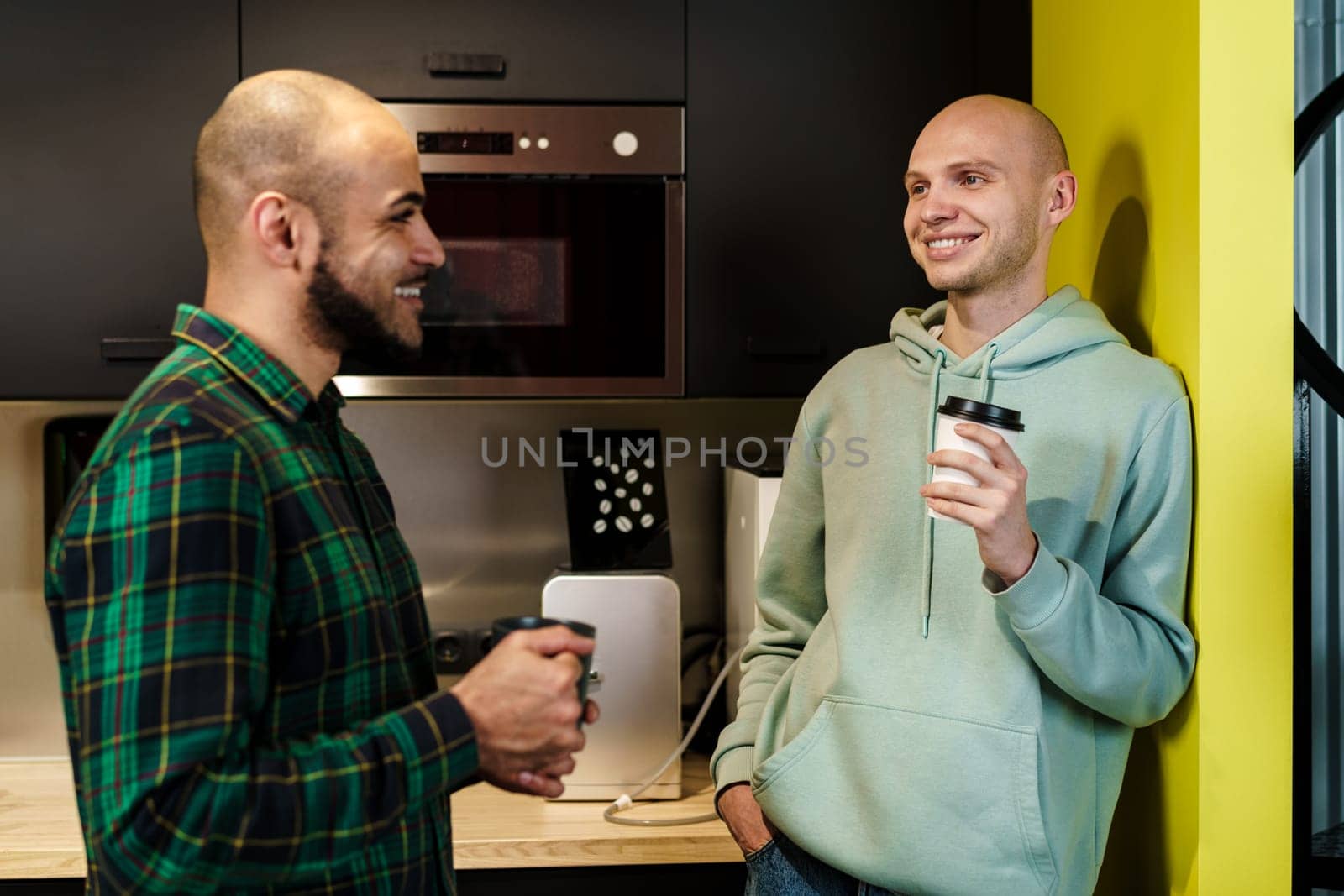 Two male colleagues having a talk while coffee break in office, close up